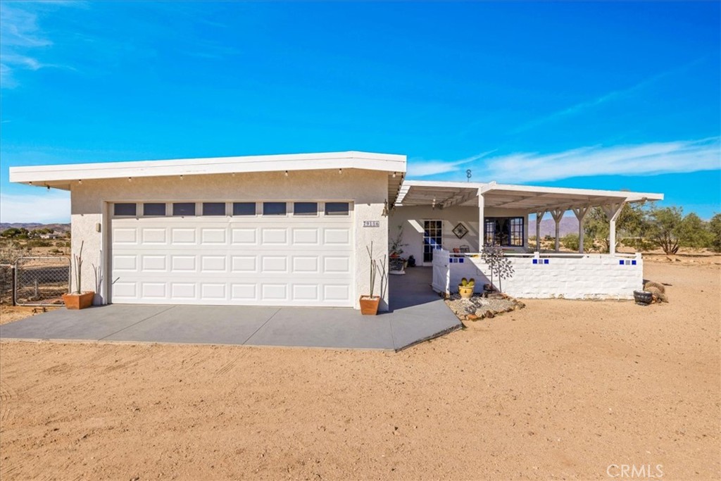 Welcome to 79116 Becker Lane, a lovely 2bed/1bath home nicely situated on a combined 10 ACRES OF LAND (two 5 acre parcels) with stunning panoramic desert and mountain views. Minimalistic living with all the comfort, this home features 1,376 square feet of living space with dual cooling (central AC/heating AND an evap cooler), an attached 2 car garage and a shared well between the two 5 acre lots. The warm and welcoming living room adorns gorgeous knotty pine ceilings, painted concrete floors, a brick-faced fireplace and several large windows that let in an abundance of natural light. The living area flows effortlessly into the quaint kitchen and dining space complete with earth-toned tile flooring, white cabinetry with a corrugated metal backsplash and a kitchen island with a sink and additional storage. The 2 bedrooms are of generous size and feature ceiling fans, concrete floors, built-in closets/shelving & they share the hall bathroom which boasts a dual sink vanity and a shower/tub combo. That's just the inside, outside you'll be delighted to find a large covered patio, mature desert plants and natural landscaping, an oversized carport, a fenced-in yard in the back and ample space to entertain or relax around a firepit on a starry desert night. This home is located less than 15 mins to the JTNP East Entrance as well as local shops, eateries, downtown 29 Palms & more; but still far enough away to fully enjoy all the peace and serenity our beautiful desert has to offer. A property like this rarely becomes available, come take a look & let this home's charming allure do the rest. Your new desert home or weekend retreat awaits.