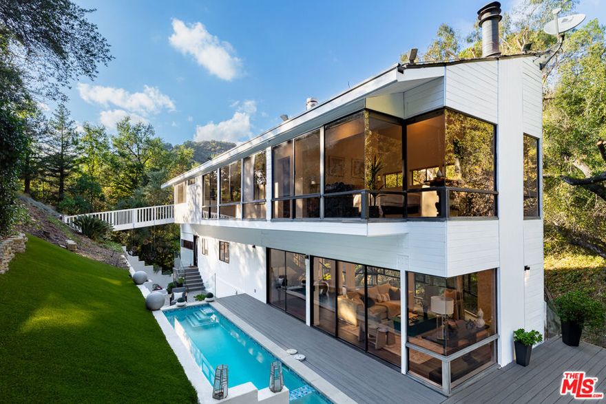 Experience ultimate privacy in this woodsy retreat hidden away from it all: Tucked behind gates and up a private, approximately 200-foot-long driveway rests this charming Benedict Canyon hideaway, positioned amidst mature trees and lush vegetation. Live a lifestyle in divine harmony with nature and views of verdant greenery from every room. Inside, wide-plank floors lead from each space to the next as large picture windows and walls of glass welcome natural light within. A greenhouse breakfast nook is adjacent to the remodeled kitchen, with its beautiful center island, dazzling backsplash, stainless-steel appliances, bright white cabinetry, and on-trend fixtures and finishes. The formal living room is centered by a decorative fireplace and offers wraparound views of the grounds and the surrounding hillside environment. The primary suite is a serene refuge and has a bathroom with dual-sink vanity and separate shower and jetted tub as well as a walk-in closet. Other bedrooms provide a unique, comfortable treehouse feel reminiscent of summer camps and family vacations. There is also a remodeled guest house with kitchenette, side patio, and bathroom. Numerous outdoor amenities include grassy lawns, rolling hills, meandering cobblestone pathways, a built-in barbecue, pool, spa, lounging decks, water features, and plenty of spaces to relax and dine al-fresco. Located within the attendance boundaries of the award-winning Warner Avenue Elementary School. Welcome home! Also available for lease.