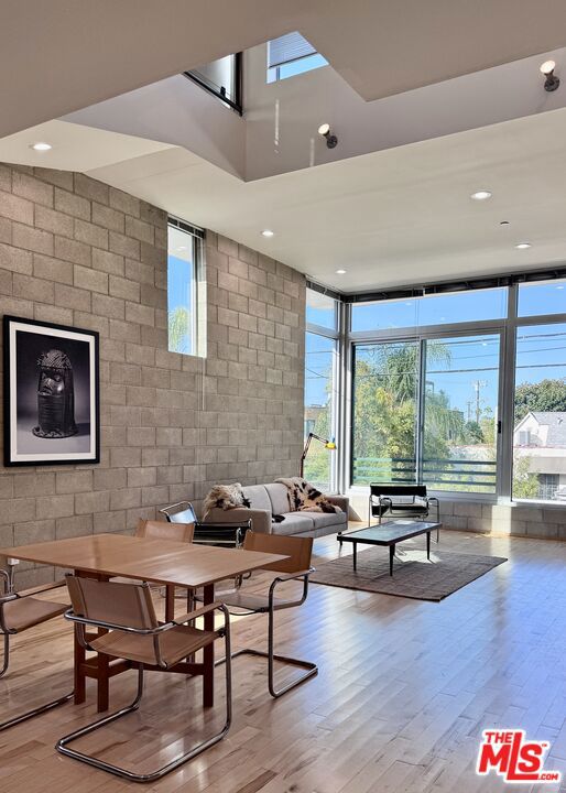 Jay Vanos Architects, 2005. True loft for lease in the area along Melrose where the West Hollywood, Hollywood, Beverly-Grove and Hancock Park neighborhoods all meet. This "Media District" features great restaurants, shopping and quiet tree-lined streets check-by-jowl with Jeffrey Deitch Gallery, Tartine Bakery and Hollywood production companies (literally across the street from Pizzeria Mozza; Petit Trois; The Cat & Fiddle and more).  This quiet, sunny, rear corner unit, one of the largest in the 27-unit condominium, opens through large windows to lush plantings to the west. Enter via a gate on Highland; the rear gate or drive into your private garage. Fully live-work; low-traffic businesses are allowed under the commercial zoning here.  The lower level can be partitioned off or entirely used with the garage for a studio/workshop (as it is currently) with its own mini-split for heating and cooling. Soaring ceilings on the main level one flight up, with one grand volume for living, cooking and dining. The flex/guest bedroom or office on this level has its own full bathroom. The top level is the primary suite, open to the level below.  A bridge here leads to the spacious roof terrace with sweeping views south, west and north to the Hollywood Hills.