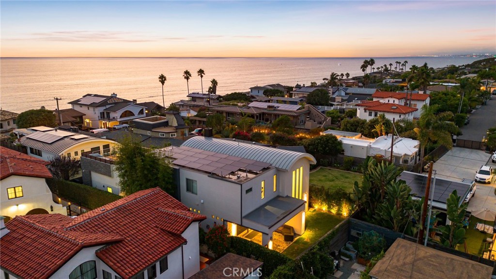 Positioned along one of Encinitas’ most sought-after coastal streets, this modern residence blends striking architecture with the relaxed elegance of beachside living. Bathed in natural light and just moments from some of North County’s most iconic beaches, the home offers a lifestyle that is both vibrant and serene. A distinctive curved roofline, bold architectural lines, and expansive windows define the design, creating interiors that feel airy and connected to their surroundings. The expansive rooftop deck serves as a true highlight, perfect for entertaining or unwinding complete with lounge seating, a fire feature, and a private sauna that transforms the space into a retreat-like escape. Inside, an open-concept layout seamlessly connects the main living spaces, anchored by a chef’s kitchen appointed with refined finishes. Multiple balconies and thoughtfully designed outdoor areas enhance the indoor/outdoor connection. A generous garage, off-street parking, and lush landscaping provide privacy while keeping local beaches, dining, and the boutiques of downtown Encinitas within easy reach. Set along Neptune Avenue, this residence captures the essence of modern coastal luxury in one of Southern California’s most desirable locations.