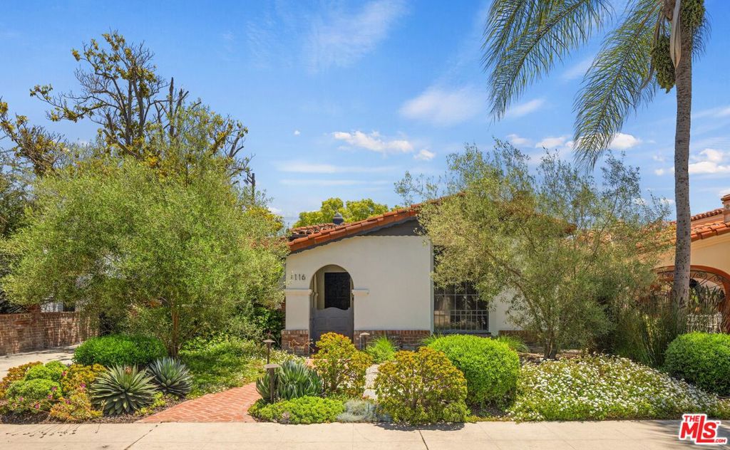 This enchanting 1930s Spanish home blends timeless architecture with thoughtful updates, offering both warmth and functionality. A brick-paved walkway and trickling fountain lead you to the formal entry, setting the tone for what's inside. The 1,886 sq ft main house features three bedrooms and two bathrooms. A generous living room welcomes you with a wood-burning fireplace, original painted beams, and a west-facing stained glass window that fills the space with natural light and vibrant color. Refinished hardwood floors flow throughout, connecting the formal dining room to the kitchen and family room. The kitchen is fitted with GE, Frigidaire, and Bosch appliances, topped with Ann Sacks tile that brings warmth and texture to your meal prep space. At the heart of the home, a private central courtyard invites you to linger outdoors. Anchored by a brick oven that doubles as a fireplace, it's perfect for al fresco dining, whether you're sharing wood-fired pizzas, slow-roasted meals, or simply gathering around its glow with friends. French doors in the spacious primary suite open to a lush backyard oasis framed by olive, lime, and kumquat trees, offering plenty of room for both entertaining and quiet retreat. The property also includes a detached 600 sq ft (approx.) guest house with one bedroom, one bathroom, and an open living/dining/kitchen layout. Delivered fully furnished, it's ideal for a home office, studio, or visiting friends and family. Set in a central pocket of Los Angeles, this home puts you close to everything. Enjoy quick access to Beverly Hills, The Grove, LACMA, and the Farmers Market. Whether you're headed to downtown, Century City, or the beach, you're about 15 minutes away in any direction with easy freeway access. Tree-lined streets and nearby cafes add to the everyday charm, while cultural destinations and shopping are right around the corner. Come tour this gorgeous home in person!