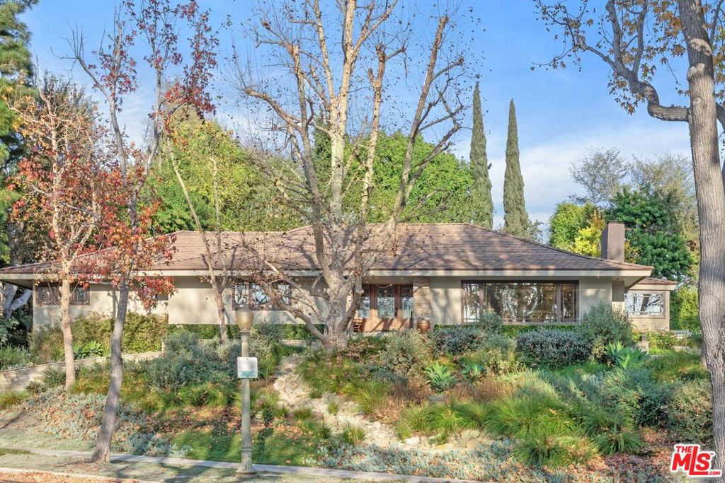 Nestled on a knoll above a tree-lined street in the heart of prestigious Little Holmby, this beautifully remodeled craftsman style single-story home blends timeless charm with modern updates. Perfect for entertaining, the expansive corner lot offers exceptional privacy and a lush, drought-resistant yard. Complete with a large circular driveway, pool, brick patio with outdoor fireplace, built in bbq, pergola, and additional lounging areas ideal for large or small gatherings, this home is ideal for California living. Inside, a thoughtfully designed floorplan places all common areas on one side and private bedrooms on the other, creating seamless flow and functionality. The spacious primary retreat boasts generous closet space and direct access to the serene rear yard. The picturesque prairie windows capture the beautiful foliage from every room. Additional highlights include two fireplaces, a study, a gym (formerly a bedroom), and a stunning chef's kitchen with an oversized center island, breakfast nook, custom cabinetry and high end appliances for the fussiest chef! Upgraded with smart features and security system, this property is move-in ready, and furniture is also available for purchase. With its single-level design and easy maintenance, this home in one of Los Angeles' most sought-after neighborhoods is truly special.