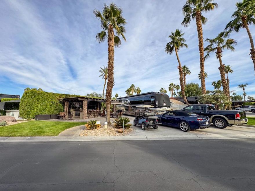 Outdoor Resort Indio is a Class A Motorcoach resort. This is an RV lot. This exceptional, oversized pie-shaped lot is one of the largest golf course properties in the resort. Perfectly situated behind the 6th tee box. The lot's extra-wide frontage provides abundant parking for multiple vehicles, with the opportunity to expand further. Conveniently located directly across from the clubhouse, main pool, and pickleball courts, you'll enjoy unparalleled access to the resort's top amenities. As the sun sets, the beautifully lit landscape creates an inviting ambiance, making this lot an entertainer's dream for hosting friends and neighbors.Designed for luxurious outdoor living, the lot features a beautifully upgraded kitchen with stainless steel appliances, granite countertops, a BBQ, large ice maker, refrigerator, double sinks, and a pop-up TV for entertaining. The spacious pergola with tiled flooring offers comfort and shade with electric drop-down screens on three sides, under-counter lighting, a ceiling fan, and two outdoor heaters for comfort. Thoughtful landscaping and paver accents create a welcoming and pet-friendly environment. With ample living space and the potential for a large casita, this lot provides the perfect blend of luxury, convenience, and privacy for the discerning RV owner. Plumbed and wired for a dishwasher.