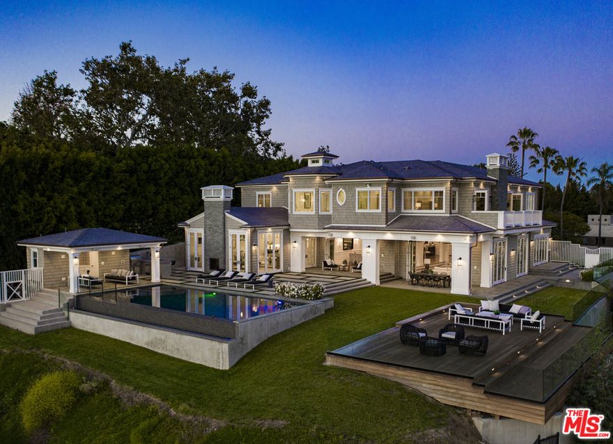 Perched on its own promontory in prime Pacific Palisades, this custom built Hampton style home is ready for an individual or family looking for a large-scale open plan home with ultimate privacy and spectacular panoramic views of the Pacific Ocean and the Santa Monica Conservancy. The quality and detail throughout the home begins as you enter into a grand foyer flowing seamlessly into the living, dining & entertaining areas. The chef's kitchen is expertly fitted & finished with only the very best appliances for cooking and entertaining. Looking out, there is an infinity pool, spa, extending deck & outdoor entertaining space. The large spacious Master Suite has a private balcony, a fireplace, individual couples bathrooms & large closets with an adjoining steam shower in the center of the bathroom. There are 6 additional en-suite bedrooms & has a 10 seat movie theatre, 960 bottle wine cellar, a gym & a billiard room. This house is a must-see for anyone looking for something extraordinary