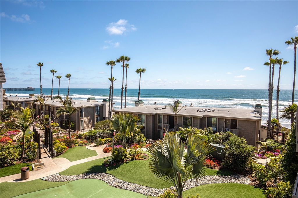 Enjoy wonderful views to the Oceanside Pier and beyond from the moment you enter this fully furnished beach home. These views are shared with the master bedroom and also include views of the lush garden. South-facing, in the tower building closest the sand and ocean, this home receives a lot of sun, breezes, and natural light. The interior is full of upgrades: a new fireplace and floor-to-ceiling mantle, slab granite counters throughout, ceiling fans, travertine backsplash, and stainless steel appliances. All furnishings are to convey. North Coast Village offers billiards, ping pong, a fitness center with sauna, and a barbecue area overlooking the pool for parties. The complex consists of ten four-story buildings surrounded by 2-story cottages, on several acres of beautifully landscaped grounds with streams, waterfalls, and tropical gardens. You are just steps from the sand; there are no roads to cross-this is an OCEANFRONT COMPLEX! Swim in the large lagoon-style heated pool (one of two pools and spas), or enjoy a romantic walk on one of the most beautiful stretches of beach in Southern California. You will also find reserved garage parking, cable television, a recreation center, clubhouse with kitchen, massive stone fireplace and cedar walls, as well as laundry facilities. North Coast Village is located between the Oceanside Harbor and the Oceanside Pier, and is a favorite destination for people from around the world. This is a great area for riding bikes! A beautiful, scenic bike trail starts right across the street from the complex or bike along HISTORIC Pacific Coast Highway. Experience spectacular sunsets and enjoy a relaxing dinner along the picturesque adjacent harbor which features several excellent restaurants, great live music, and fun and unique shopping. There are also kayak, boat, and paddle boat rentals, and fishing or whale watching excursions. Downtown Oceanside is a neighborhood that knows its potential. With brand new renovations recently compl...