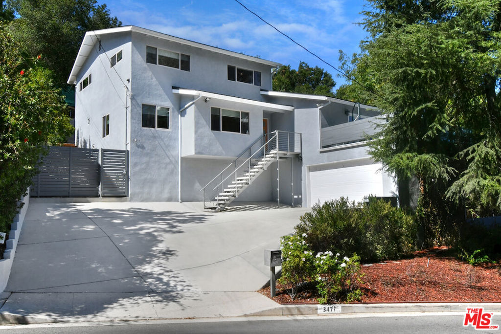 This contemporary retreat is set back from the street, offering city and mountain views. Open floorplan with hardwood floors, a living and dining area with a fireplace, and double glass doors that lead to a large view terrace. The kitchen includes a great center island, stainless steel appliances, custom cabinetry, and a breakfast area. Upstairs, there are three bedrooms, including the primary suite with a private attached bathroom featuring double sinks, a glass shower, and a custom walk-in closet. Additional features include recessed lighting, new interior paint, and artistic stonework in all bathrooms. A private back patio and terraced garden offer a peaceful outdoor space. The extra-large two-car garage is finished and has an additional secure storage room. Conveniently located near Mulholland Drive, with easy access to the Westside, Century City, and Beverly Hills.