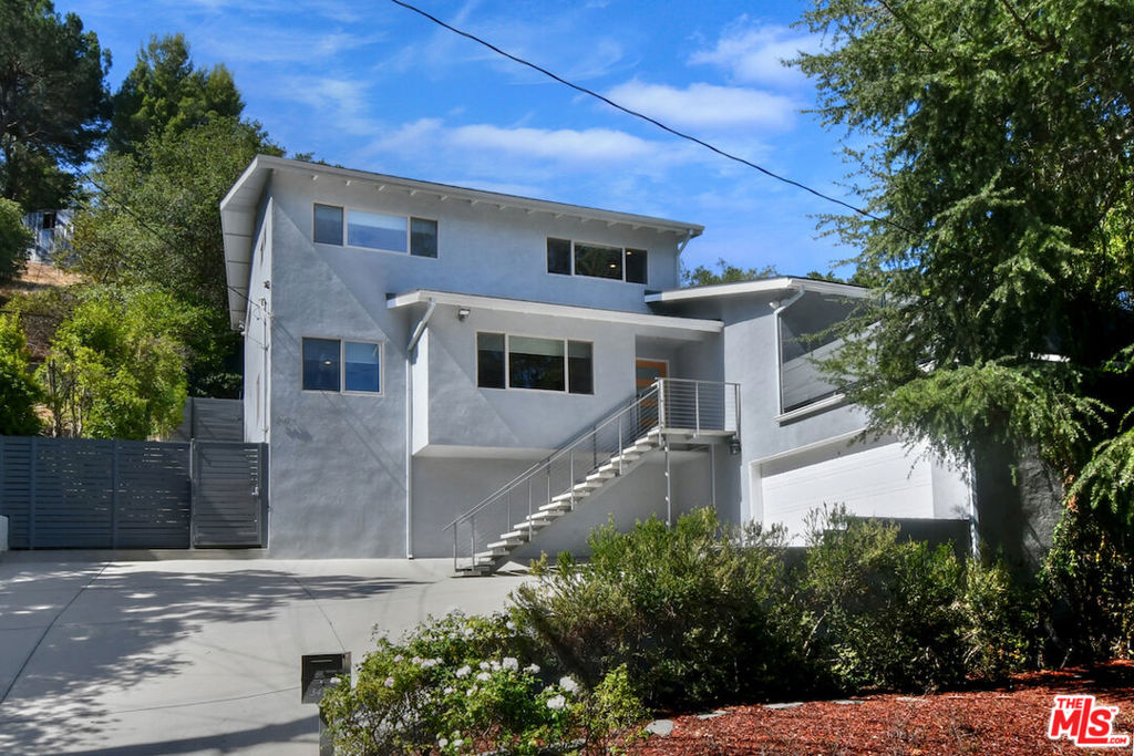 This contemporary retreat is set back from the street, offering city and mountain views. Open floorplan with hardwood floors, a living and dining area with a fireplace, and double glass doors that lead to a large view terrace. The kitchen includes a great center island, stainless steel appliances, wine refrigerator, custom cabinetry, and a breakfast area. Upstairs, there are three bedrooms, including the primary suite with a private attached bathroom featuring double sinks, a glass shower, and a custom walk-in closet. Additional features include recessed lighting, new interior paint, and artistic stonework in all bathrooms. A private back patio and terraced garden offer a peaceful outdoor space. The extra-large two-car garage is finished and has an additional secure storage room. Conveniently located near Mulholland Drive, with easy access to the Westside, Century City, and Beverly Hills.