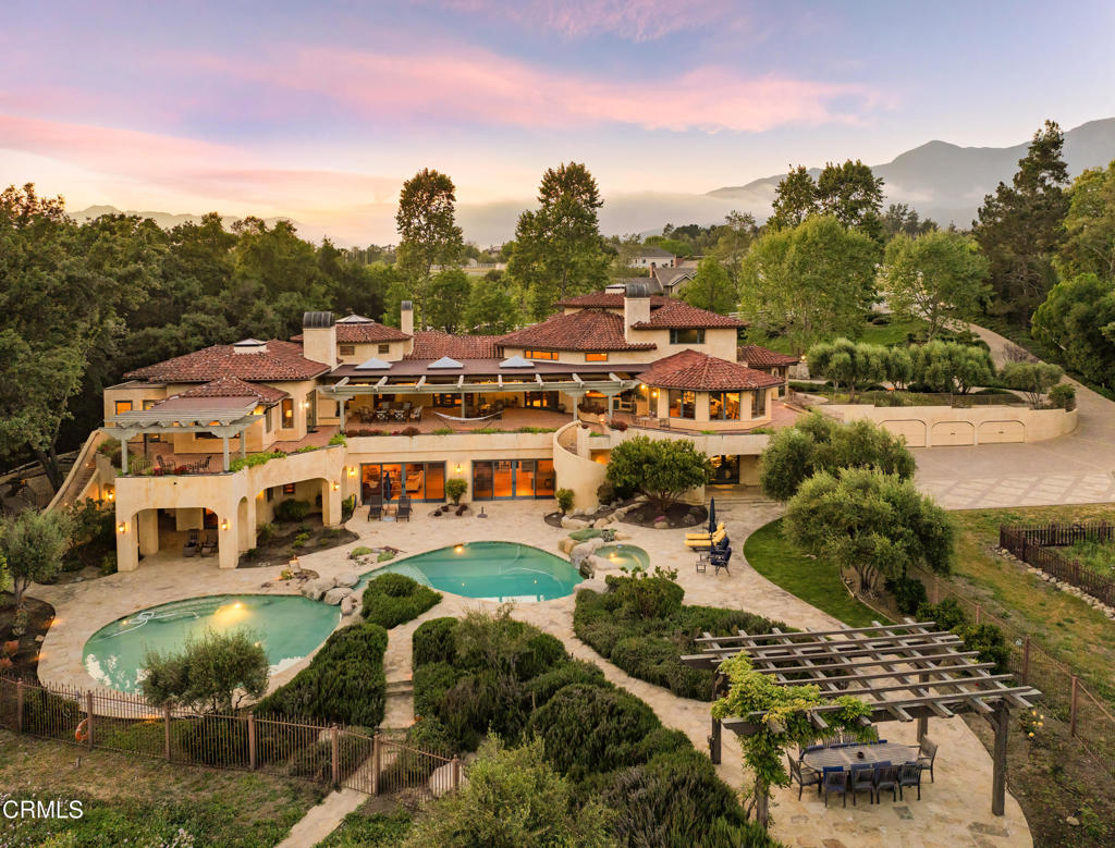 Magnificent Ojai estate nestled on approximately 3.8+/- acres, offering sweeping views of the Topa Topas, masterfully merges timeless old-world aesthetics with contemporary California artistry. This exquisite Mediterranean-style residence--designed by acclaimed architect Marc Whitman--is a rare offering that combines privacy, elegance, and craftsmanship at the highest level. Curved lines, arched doorways, and cathedral ceilings set a tone of quiet grandeur. Inside, every detail has been meticulously curated--from solid walnut flooring and bespoke cabinetry to imported Spanish tiles, hand-forged chandeliers, and custom windows and hardware. The expansive living room, featuring multiple seating areas, a fireplace, and French doors, opens to a private library and a sunlit patio, perfect for indoor-outdoor living. The gourmet kitchen, with top-tier appliances and panoramic views, is both a culinary haven and a gathering place. The primary suite is a sanctuary with two sitting areas, a fireplace, double doors to a private terrace, stunning mountain vistas, generous closets, and a spa-inspired bathroom. Three guest bedrooms, each with ensuite bathrooms and access to patios and gardens, offer ultimate comfort and privacy. A fifth bedroom occupies the top level--complete with a loft, fireplace, and two balconies--ideally suited for an office, studio, guest retreat, or live-in support. With multiple bedroom suites and separate living zones, the estate offers exceptional flexibility for multi-generational living or those seeking refined personal space. The top-level suite also serves as a unique option for a private executive office or creative retreat. Seamless transitions from the interior to the outdoors--through French doors and strategically placed terraces--extend the living experience to sunlit decks, lush gardens, and an inviting pool area. Whether envisioned as a full-time residence, a luxurious second home, or a legacy investment, this estate is a rare opportunity to own an architectural masterpiece in one of Ojai's most exclusive enclaves.