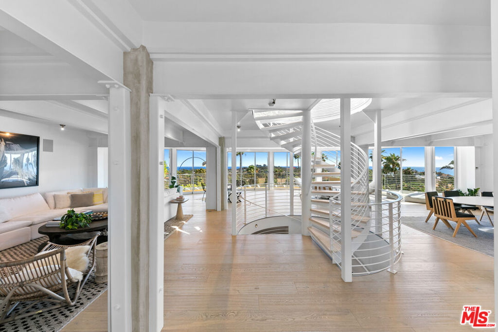 A stunning architectural masterpiece where privacy and creativity converge in the exclusive gated enclave of Cavalleri. Fully renovated with impeccable designer finishes, this home features floor-to-ceiling glass walls, White Oak floors, and a central spiral staircase. Enjoy panoramic ocean and mountain views from multiple decks, including a newly redone rooftop deck offering 360-degree vistas, an indoor wet bar, a built-in BBQ, and a fire pit. The entry level is an entertainer's dream with an open-concept layout, featuring multiple seating areas, serene coastal views, and stacking glass doors that lead onto a wrap-around deck. The dining area flows seamlessly into the chef's kitchen, boasting Miele appliances, Labradorite stone countertops, a gas range with dual ovens, and a large island with breakfast bar seating. The luxurious primary suite overlooks the sparkling Pacific and includes a comfortable sitting area, motorized drop-down television, spa-like bath with dual rain steam shower, free-standing porcelain soaking tub, and direct access to a sun-soaked patio. Two additional en-suite bedrooms and a detached guest suite provide ample space for family and guests. Outside, a grassy lawn wraps around the home, and there are plans available for a future pool. Additional features include a full-home Sonos system, remote-controlled blackout shades, a laundry room, and a 2-car garage. All set within a private, gated community on a quiet cul-de-sac with convenient trail access and a central location near local markets, schools, restaurants, pristine beaches, and more. Experience Malibu at its finest, where breathtaking beauty and refined coastal elegance come together in one remarkable home.