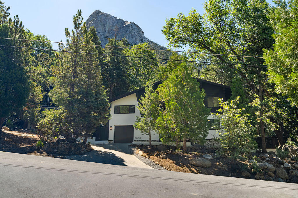 Mountain Peaks Chalet, an extraordinary, fully modernized mountain cabin nestled along a serene seasonal creek with breathtaking views of Tahquitz Rock (Lily Rock) and Suicide Rock through dramatic clerestory windows. No detail was overlooked in this complete hillside transformation: New hickory wood flooring, modern lighting, wood-burning fireplace, and a stunning chef's kitchen with custom cabinetry, quartz countertops, and stainless-steel appliances.Both bedrooms are conveniently located on the main level, including a custom primary suite, plus direct access to the finished garage featuring an EV charger, built-in cabinetry, fridge, and sink. Upstairs, the open-concept living area dazzles with forest views on all sides with wood-burning high efficiency stove w/catalytic converter for near-zero emissions, a spacious balcony, flexible den/office (or additional sleeping space), and a stylish new guest bath.Enjoy year-round comfort with 5 new electric mini-split heating/AC units, all-new windows and doors with custom shades (some remote-controlled), fresh interior/exterior paint, a new roof, and refreshed landscaping with new rock and mulch. Ideally situated close to town and scenic hiking trails, Mountain Peaks Chalet is the perfect blend of modern luxury and timeless mountain charm.