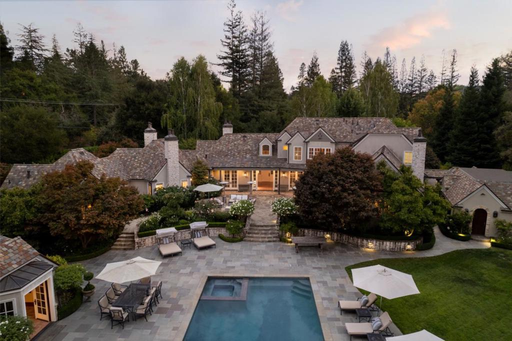 Set on just over one acre, this home makes a commanding first impression w/its ivy covered walls, stone accents & leaded glass windows. Sophisticated style and classic elegance unfold across two levels with hardwood floors in most rooms, some Venetian plaster walls, and towering architectural ceilings. This 6-bedroom home has the primary suite on the main floor & one additional bedroom presently used as a study center off the kitchen. All bedrooms are en-suite. In addition to the 4-bedrooms on the second floor is a central media/play lounge with built-in cabinetry. There is a 2 bedroom, 2 bath guest house with full kitchen. Indoor/outdoor living is yet another signature of this home with its salt-water pool, spa, outdoor kitchen & heated lounge, plus a sport court. All surrounded by vast terraces & level grounds in complete privacy. Attached to the garage/carport (1060SF) is a customized wine cellar. Las Lomitas schools. Close to Stanford & Sand Hill Road venture capital centers.