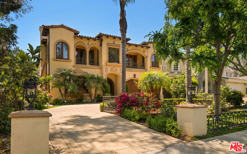 Step into timeless elegance at this stunning Mediterranean estate in the heart of Brentwood. Tucked behind lush hedges and framed by mature palms, this grand residence offers unparalleled privacy and sophistication. Enter through a dramatic double-height foyer with a sweeping wrought iron staircase, domed ceiling, and ornate chandelier. The spacious formal living and dining rooms are designed for entertaining, accented by arched entryways, rich wood detailing, and natural stone floors. An expansive chef's kitchen anchors the home, featuring a massive marble island, top-of-the-line Viking appliances, walk-in pantry, and a breakfast nook that overlooks the backyard. The residence offers multiple family and entertaining spaces, including a warm family room with a fireplace, custom cabinetry, and seamless indoor-outdoor flow through French doors. A wood-paneled office with built-ins provides the ideal work-from-home setup. Upstairs, the luxurious primary suite is a true retreat - complete with a cozy sitting area, fireplace, and French doors that open to a private balcony. The spa-like primary bath boasts dual vanities, a soaking tub surrounded by arched windows, and two oversized walk-in closets with custom storage. Additional bedrooms are generously sized and beautifully appointed, each with en-suite bathrooms. Step outside to your own private oasis - complete with a sparkling pool, elevated spa, outdoor fireplace, and multiple lounge areas surrounded by vibrant landscaping. This tranquil backyard is ideal for both intimate gatherings and large-scale entertaining. Located moments from Brentwood's best shops, dining, and schools, this exquisite home combines Old World charm with modern comforts in one of LA's most desirable neighborhoods.