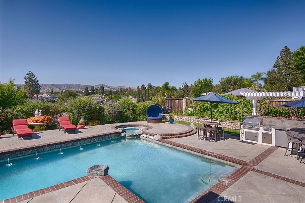This one is worth a look! Beautifully updated 4 bed 3 bath home with spectacular yard, views and a massive 450 square foot patio within walking distance of Yorba Linda Country Club. Curb appeal is outstanding with fresh designer paint, a beautifully manicured yard, even a rock bridge. Walk through the double door entry onto new floors. Notice the oversize marble fireplace (there are 3 fireplaces) and open beam ceilings. There's a main floor bedroom and updated bath with shower. The kitchen has been enlarged and perfectly updated with current finishes. It's nice and bright and opens to that fantastic patio. The family room is big with a fireplace, built-ins and a view. Upstairs find 2 large bedrooms and the Primary suite. Let's talk about the primary bedroom...this retreat stretches across the back of the house and includes a fireplace, sitting area, coffee/wet bar, 2 walk-in closets an updated bathroom with walk-in shower and Jacuzzi tub! Enjoy your coffee on the balcony and drink in views to Carbon Canyon. Stepping outside, the backyard wouldn't be out of place at a resort. The large salt water pebble-tec pool is flanked by an outdoor kitchen and bar area on one side and a Koi pond, fountain and fire pit on the other. Many say their home is an entertainers dream, this one really is. You will also find an outdoor office with mini split for heating and cooling. Nearby schools are excellent. Don't miss this unique and wonderful home. Professional photography coming soon.