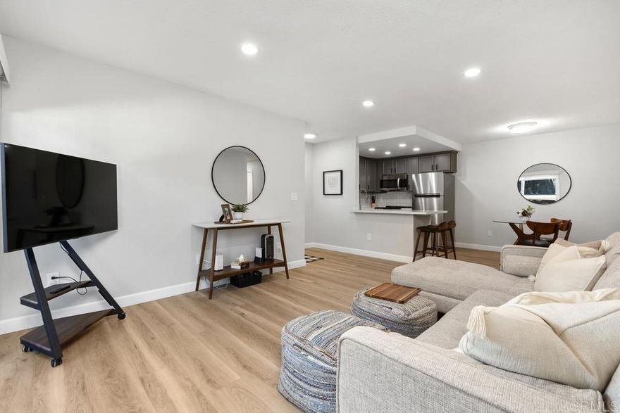 Inspiration meets design in this gorgeous, remodeled two-bedroom, 1.25 bath condo. From the moment you arrive, the smart front door makes an impression, with privacy glass that shifts from frosted to clear at the touch of a button and keyless fingerprint entry for effortless coming and going. Inside, wide-plank LVP flooring flows throughout, tying together a soft, neutral paint palette, smooth ceilings, and recessed lighting with dimmer switches. The kitchen is fresh and thoughtfully updated with quartz countertops, refinished cabinetry and hardware, a deep single-basin sink with tall pull-down faucet, stainless steel appliances, and a daily dining bar that opens to the adjacent dining area. The beautifully updated bathroom features a floating vanity with a quartz countertop, designer mirror and lighting, a tiled shower surround with a soap niche, a sleek semi-frameless shower door, and upgraded fixtures. Just off the bathroom, a matching vanity area for the spacious primary bedroom adds the convenience of a dedicated dressing space, and this area also includes a large linen cabinet for extra storage. The primary bedroom also offers a large walk-in closet with a custom closet system, while the secondary bedroom is generously sized and ideal for guests, a home office, or flex space. Pocket doors have been added throughout to maximize space and functionality, and new dual-pane windows plus an 8-foot slider are designed for comfort and energy efficiency. The large private patio extends your living space outdoors and includes a convenient walk-in storage closet. All of this is set within a gated community that offers a pool, spa, barbecue area, and beautifully landscaped green spaces with mature trees throughout. The location also provides a quick drive to the beach, easy freeway access, and shopping and restaurants typically within 5 to 10 minutes. With so many thoughtful upgrades already in place, this is truly a move-in-ready home you can start enjoying from day one.