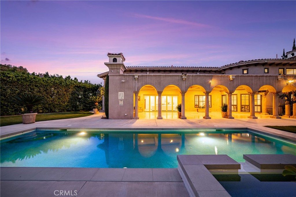 Stunning gated estate in prestigious Villa Park. This once in a lifetime gem known for its exquisite all plaster exterior, grand portico with stunning Venetian columns and ornate iron entry doors that set the stage for the masterpiece of luxury and sophistication that define this stunning home. With 7632 square feet of living space spanning an unprecedented 39,030 sqft lot, this estate offers an unparalleled living experience with all the comforts of home. The grand staircases are adorned in gold leaf accents on wrought iron with a crystal chandelier above and sconces lining the walls of each flight and hand plastered walls are found t/o. An exquisite library off the entry is a true draw with its wainscot walls and gorgeous coffered ceilings. Adjacent is the formal dining room with a custom painted arched ceiling and french door access to the serene outdoor setting. The newly built kitchen is a true showstopper as sleek waterfall quartz cascades vertically over the islands edge. Appliances include double dishwashers, a six burner range with double ovens, additional built in oven, microwave, warming door and refrigerator. Entertaining is effortless in the expansive great room with its dual sitting areas, wine cellar a wonderfully placed long bar with built in storage racks, wine refrigerator, sink and an abundance of cabinetry. The five bedrooms offered includes one main floor bedroom with private access and an en-suite with it's own egress to the splendor of the private outdoor setting. A residential elevator ensures comfortable access to every level. The primary suite is accessed via a private corridor lined with crystal sconces and an arched tray ceiling. The suite includes a sitting room with fireplace, an office, French doors to a balcony with serene views, two well planned walk-in closets, a private sauna, a spa style walk-in shower, a freestanding tub, and abundance of beautiful cabinetry. Another wonderful sitting room with fireplace plus 3 more bedrooms all with en-suites, a gym area, and two balconies each with views, complete the second floor. Whether you're relaxing by the pool or entertaining guests under the logia with its glistening travertine flooring, this timeless estate offers tranquility and style. Every corner of this home speaks to a refined sense of taste and a commitment to comfort. From the Venetian inspired design elements to the cutting edge remodel, this estate is truly a rare find where classic luxury meets modern convenience.