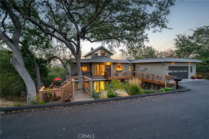 Welcome to Junipero Oaks Vista. Designed and built by renowned, award-winning sustainable builder Turko Semmes, this custom residence naturally balances elevated living and harmony with the land through its thoughtful and energy efficient passive solar design. Tucked within a private, oak-studded setting, the home captures sweeping views of the Salinas River Valley and rolling hills, while offering effortless access to the revitalized downtown Atascadero, world-class wine tasting in Paso Robles, and shopping in San Luis Obispo. Situated on a nearly one-acre parcel, the welcoming floor plan offers approximately 2,550 square feet of flexible living space with three spacious bedrooms, three well-appointed baths, plus a versatile loft. Stepping into the comfortable living and dining rooms you are greeted with Mahogany woodwork, stamped concrete flooring, curved wall details, a handmade candelabra, and the peaceful panorama created by front to back windows. With custom two-tone cabinetry with soft close features, quartz countertops, Bosch dishwasher, Frigidaire gas range, Whirlpool low profile microwave, and an included Samsung refrigerator, the centrally located kitchen is the social hub of the home. Glass French doors open to a media room with custom designed in wall surround sound speakers and Hunter Douglas window shades creating the perfect ambiance for watching a movie or hosting a game night. A tranquil retreat, the primary suite offers a sitting area, walk-in closet with organizers, en-suite bath, and access to a spa-ready deck. Two secondary bedrooms, each with sliding glass doors opening to the serene landscape, enjoy access to an adjoining full bath creating convenience for guests. Multiple outdoor living areas include three expansive composite and wood decks, accented by redwood and iron railings. The thoughtfully designed landscaping creates a relaxed setting, enhanced by solar lighting. Meandering concrete and flagstone steps lead to lush garden beds, a compost area, and a canopy of more than 70 oak trees, complemented by striking Japanese Maple, California Buckeye, and Flannel trees. A level area at the lower portion of the parcel provides an opportunity for a bocce/sport court or potential ADU. Additional highlights include a detached two-car garage with automatic opener and 220 wiring for future EV charger, owned solar system, Mitsubishi multi-zone inverter heat pump, water softener, kitchen reverse osmosis system, and attic fan.