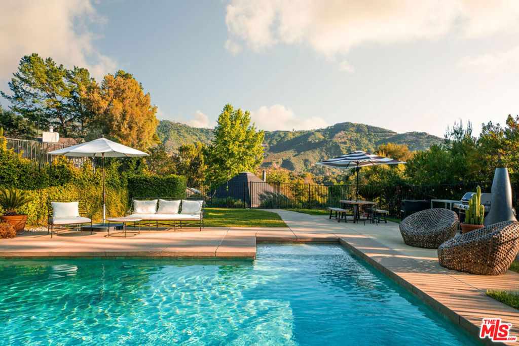 Tucked away in highly sought-after Monte Nido, just beyond the storybook Edenwild bridge and nestled on a peaceful cul-de-sac, this warm and inviting five-bedroom, three-bathroom home creates the perfect balance of comfort, privacy, and connection to nature. Surrounded by the breathtaking Santa Monica Mountains, this home is the essence of elevated California living. Step inside where soft natural tones create an instant sense of welcome. Sunlight streams through floor-to-ceiling windows, illuminating the spacious living room with soaring vaulted ceilings and a statement fireplace perfect for cozy evenings. The inviting chef's kitchen showcases premium Thermador appliances, handcrafted Heath Ceramic tile backsplash, sleek Caesar-stone countertops, and a generous island that opens to the family room and view-filled balcony ideal for your morning coffee to an evening glass of wine. Throughout the home, you'll find blonde oak flooring and thoughtful architectural details that create a warm yet sophisticated atmosphere. The primary bedroom offers vaulted ceilings, a walk-in closet, and on-suite spa-like bathroom. Four additional guest rooms provide versatile space for comfortable family living, welcoming visitors, and pursuing creative endeavors. Your private saltwater pool and spa is perfectly positioned to capture sweeping mountain views. Multiple terraces, patios, and outdoor dining spaces make this a true entertainer's paradise. A detached office/studio/gym provides flexibility for remote work, creativity, or wellness. Located just steps from scenic trailheads for glorious hiking and minutes to the beaches of Malibu, Calabasas Commons, and top-rated Las Virgenes schools, this property is more than a home, it's a gorgeous lifestyle.