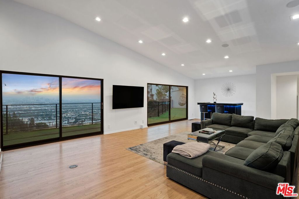 Experience modern luxury at its finest in this 4-bedroom, 5-bathroom contemporary estate perched above the iconic Sunset Strip. Set against sweeping panoramic views of the Los Angeles skyline, this retreat offers an open floor plan flooded with natural light and seamless indoor-outdoor living.The main living room features floor-to-ceiling windows and sliding glass doors that frame the breathtaking vistas, while the sleek gourmet chef's kitchen boasts a large center island and top-of-the-line stainless steel appliances. The lavish primary suite opens to a private balcony and outdoor living space, complemented by three additional ensuite bedrooms for family and guests. Designed for both relaxation and entertaining, the home includes multiple terraces, an outdoor BBQ, surround sound speakers, and an above-ground pool and spa for added leisure. Additional amenities include a temperature-controlled wine cellar, gated entry with security cameras, solar power systems, and a two-car garage. Just moments from world-class dining, shopping, and entertainment, this fully furnished Hollywood Hills sanctuary is move-in ready and waiting to be enjoyed.