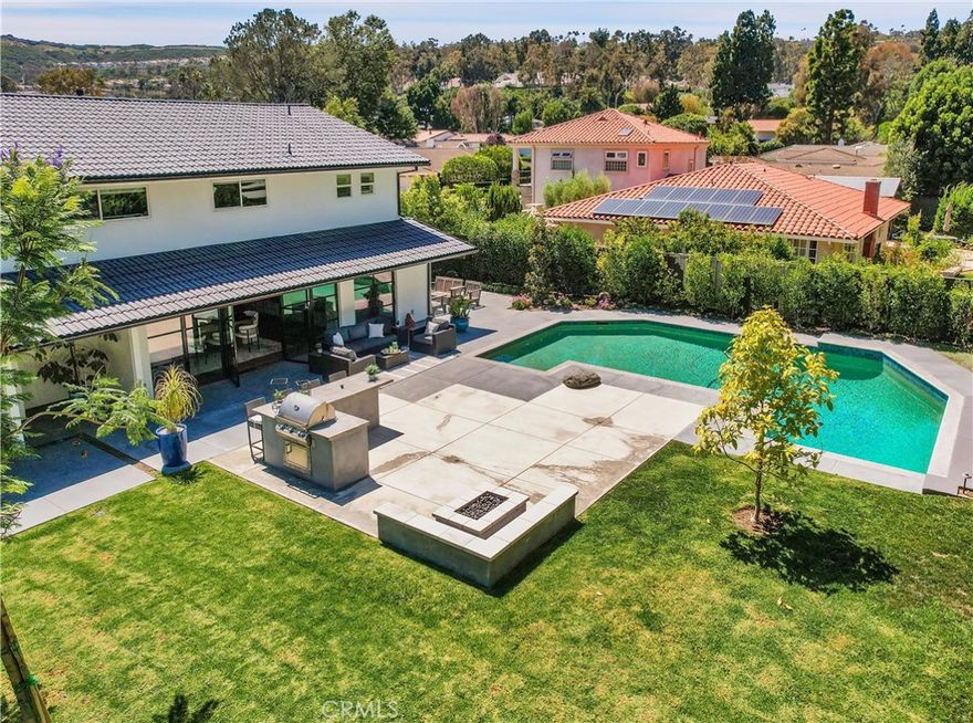 Stunning reimagined contemporary styled home with sleek clean lines, light filled spaces framed by natural materials, boasting a spectacular entertainer’s backyard haven and a superb location just across the street from El Niguel golf greens. The highly manicured front yard and striking exterior features create a dramatic first impression. Pass through the gated front entrance where you are greeted with lush vibrant foliage framing a private courtyard leading to the striking glass door entrance. Step through to the astonishing Great Room, a spectacular open concept space with living room seating area open to the airy dining space and stunning kitchen, with warm Mediterranean Oak plank floors and a wall of metal framed windows and French doors providing soothing views of the backyard, a perfect indoor-outdoor living space for entertaining. The luxurious chef’s kitchen is a masterpiece boasting a 14 ft island with Brazilian Marble waterfall countertop, sleek European style cabinetry, and professional grade appliances including a Forno Italian 8 burner range and commercial fridge/freezer. The main level includes a highly prized bonus room perfect for a home office. Travel up the striking stairwell framed by a custom metal wall and glass railings to the bedroom level where you will find the primary bedroom suite, a peaceful retreat with a private sunroom and gorgeous views, perfect for enjoying an evening glass of wine with a loved one. The primary bathroom is a sumptuous space with luxurious marble features, dual vanities, a walk-in closet tucked away, a huge step-in shower and Japanese style soaking tub, your own private home spa! Each guest bedroom includes beautifully remodeled full private baths with the same luxurious marble features and fine fixtures. The backyard is a private tranquil oasis framed by lush landscaping and mature trees, with a spacious patio with built-in bar, firepit, and BBQ overlooking a large inviting pool and large grassy lawn. You will adore the detached fully finished structure hidden away in the backyard, customizable to fit your imaginings, a perfect nook for a small home office, craft room, playhouse, yoga, or meditation space! Superbly located in a highly desirable school district and within walking distance of the library, dining, shopping, and close to numerous hiking and biking trails, Laguna Niguel Racquet Club and El Niguel Country Club and golf course, minutes from Salt Creek Beach, Dana Point Harbor and Laguna Beach.