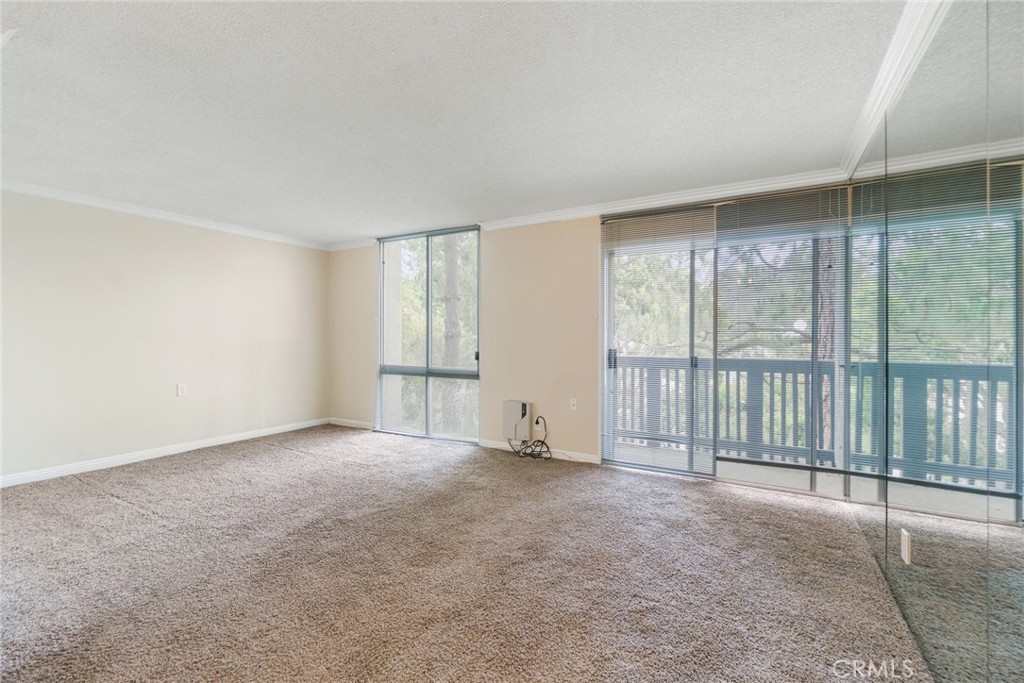 Welcome to this charming studio nestled in the heart of Rolling Hills Estates. This lower-level unit offers an open and inviting layout with large windows that let in natural light and provide views of lush, green surroundings. The living space features neutral tones, crown molding, and mirrored walls that enhance the feeling of spaciousness. Enjoy your morning coffee or unwind after a long day on your private balcony, surrounded by tranquil trees.
The kitchen is equipped with countertops, ample cabinetry, and a breakfast bar that opens to the main living area—perfect for casual dining or entertaining. The bathroom includes a granite vanity, tub/shower combo, and extra storage. Additional highlights include wall heating, plush carpeting throughout, and access to community amenities. Ideal for first-time buyers, investors, or anyone looking for low-maintenance living in a peaceful setting. Conveniently located near shopping, dining, and outdoor recreation.