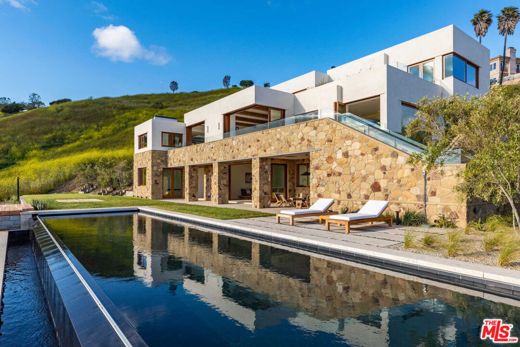 Set on 17 acres above the Pacific, this Malibu estate is reminiscent of Mallorca or Mykonos in one of California's most coveted coastal communities. Situated on a private road, a 600-foot gated driveway leads to the 10,000-square-foot retreat, immersed in the far-reaching ocean and canyon vistas. Sliding pocket doors foster a harmonious indoor-outdoor flow, leading to ample terraces and an infinity-edge pool that captures some of the most breathtaking sunsets in Southern California. An expansive upper level holds 2 ensuite bedrooms and an expansive master that may be combined to form one unprecedented living space. A rare daylit lower level serves as the ultimate wellness retreat, with a private guest suite, gym, steam room, infrared sauna, theater, wine cellar, and kitchen. Complete with an elevator, 3-car garage, ample parking, and Savant automation, the home feels worlds away from it all yet is just moments to PCH and close to Malibu Country Mart and world-class restaurants.