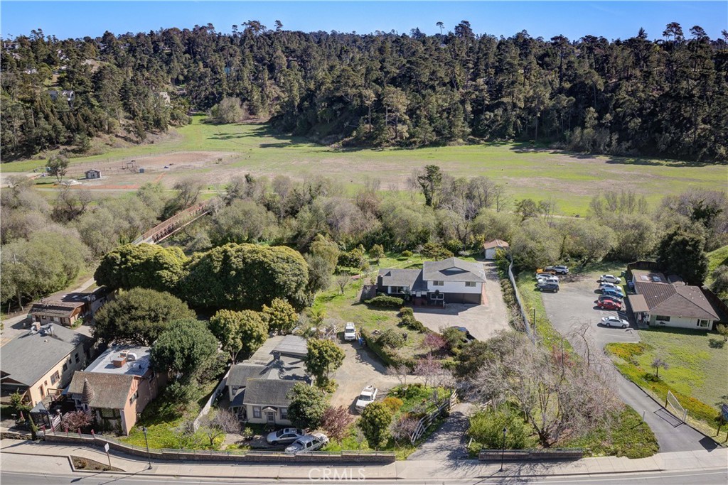 This property is truly a rare find including TWO single-family homes with TWO separate residential water meters. The larger home at the back, is a 2,287 square foot home with an open concept that was recently remodeled. The spacious living room flows into a formal dining area, a big kitchen with new cabinets, quartz countertops and featuring a big kitchen island perfect for entertainment. There is also a convenient half-bath off to the living room. A few steps down, you'll find a cozy bedroom, a three-quarter bath, a laundry room, and two expansive one-car garages. Behind the garages, enjoy a private enclosed sunroom—a perfect spot to unwind. Upstairs, the oversized primary bedroom features its own recently remodeled full bath, along with two more large bedrooms and a shared bathroom.
The second home a charming 1,032 square foot original front house has been thoughtfully transformed into a 3-bedroom, 1-bath home, complete with a cozy living room, kitchen, and a convenient washer/dryer space. The tenants of 30 years have also created a small private studio with a three-quarter bath.
Santa Rosa Creek runs along the back, with a corner of the property extending across the creek into the CCSD yard.
Parking is a breeze with a large turnaround driveway—perfect for hosting an RV, boat, or any other toys you might have. And for those who love fresh fruit, you’ll find a variety of fruit trees scattered throughout the property.
This one-of-a-kind .92-acre property offers limitless potential! With two separate meters for electricity, gas, and water, there’s also the possibility of splitting the properties—check with SLO County for details. Property is also currently eligible for a Vacation Rental License! Don’t miss out on this incredible opportunity!