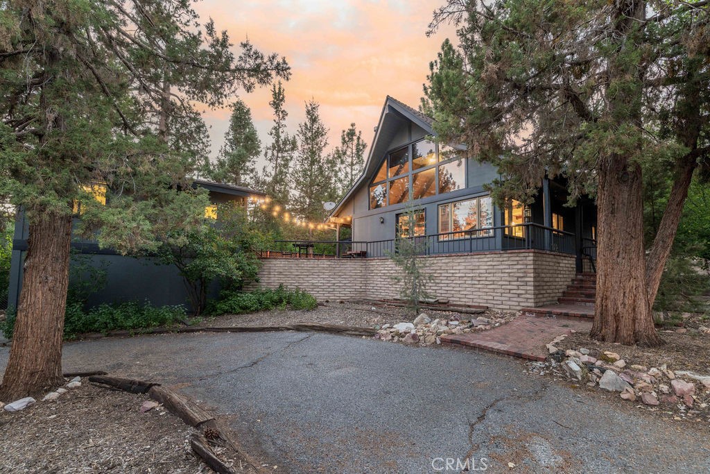 GORGEOUS CUSTOM CHALET + ADU IN WHISPERING FOREST, AT A SWEET PRICE! The Walk and Drive Score on this one is EXCELLENT! Within 0.3 miles (8 minute walk) from the National Forest at the end of the street, 1.7 miles from the lake, and approximately 1 mile from year-round fun at the Convention Center (Oktoberfest, Wyatt's, Farmer's Market), trailhead to the new paved pedal path and boardwalk through the Stanfield Marsh Wildlife and Waterfowl Preserve, Big Bear Snow Play and Raceway (go-carts), and dining––the location of this cabin is so great, and short-term rental guests rave about it too! Situated on a large corner lot surrounded by mature trees and shrubs, with plenty of parking space including a wraparound driveway and a 2-car garage. Above the garage is a spacious ADU with an updated kitchenette, dining area, bedroom and bathroom. In the main cabin, the great room boasts a wall of windows, vaulted wood and beam ceilings, a super cool mid-century modern wood burning stove surrounded by an extra long brick hearth offering additional seating. Game night or mealtime, from the living room to the kitchen and open dining, enjoy the convenience of getting to stay connected with your loved ones! Or enjoy a break and retreat to the upstairs loft with its library-like shelving, or to the master suite! Downstairs on the main level, there is another spacious bedroom with a lovely "reading nook", and a huge bathroom. Outside there is plenty of space to lounge, including a relaxing and private hot tub to enjoy peaceful mornings or evening stargazing! Whether you're seeking your own slice of paradise for a personal retreat, a short-term rental investment, or a full-time residence, this property offers incredible flexibility. Live in one unit while renting out the other for supplemental income, or maximize its potential as a full rental. This is a home you simply must see- schedule your showing today!
