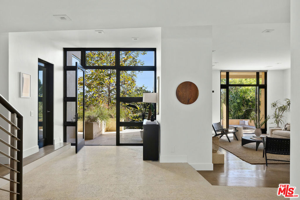 Set on a private knoll on the upside of Napoli Drive in the Riviera, this warm contemporary provides spectacular views through the treetops, making it easy to "Get away from it all." With three stories, there's plenty of room to spread out to spend time together, or to enjoy a peaceful place to work, read or create.Through the entryway, a double height foyer greets you with gorgeous views out to the backyard. One side of the main floor features a living room with fireplace and an office, offering versatility and privacy. On the other side, an inviting open layout connects the dining room, family room, kitchen, and breakfast nook, providing a warm and inviting atmosphere for everyday living. Prepare to be inspired by the chef's dream kitchen, equipped with every imaginable convenience plus an expansive view! Offering a Viking range with double ovens, large walk in pantry, and two dishwashers, this kitchen makes culinary endeavors an absolute pleasure. With two spacious islands, the kitchen offers incredible prep areas and even has sparkling water on tap. For those who appreciate a little indulgence, a kegerator is also at your service. The house has six bedrooms and six bathrooms; five up and one down. The upper level provides two distinct areas. First is a spacious primary suite with views across the Riviera golf course, a fireplace, two separate walk-in closets, a spa style bath with a steam shower and privacy window foggers. Second, you'll find four more bedrooms (one of which is currently used as a secondary office). One more private bedroom and bath is on the lower level. The backyard features a pool and spa that beckon you to relax and unwind, while the built-in banquette seating around the firepit and gracious dining area provide perfect spaces for entertaining and enjoying outdoor meals. Set just down the street from the Riviera Country Club and just minutes to Brentwood Country Mart, the Palisades Village, the beach and hiking trails, this Riviera gem allows you to enjoy all that the Palisades lifestyle has to offer.