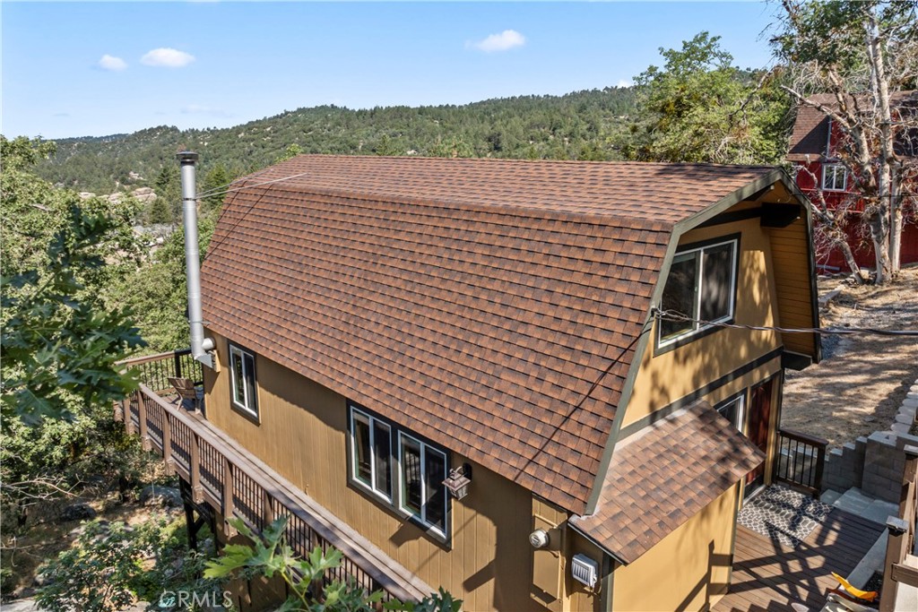 Perched on five spacious lots with sweeping views of the San Gabriel Mountains, this beautifully updated 3BR, 1.5BA home offers the perfect blend of mountain charm and modern upgrades. Originally a 2BR/1BA, the home underwent a complete transformation starting in 2018, taken down to the studs and rebuilt with a fully permitted renovation that added a third bedroom and a half bath. Spread across three levels, the thoughtful floor plan offers both privacy and flexibility, making it ideal for hosting family and friends. Throughout the home, you'll find rich Brazilian Cherry hardwood floors, tongue and groove wood ceilings with exposed beams, and new dual-pane windows and sliders that bring in abundant natural light. The main-level entry opens to a chef-style kitchen featuring a large center island, solid marble countertops, undermount stainless steel sink, solid wood cabinetry with soft-close drawers, stainless-steel appliances, and a breakfast bar. The adjacent dining area flows effortlessly into the living room, which is anchored by a wood-burning stove, a charming bay window, and access to the main deck, perfect for taking in the serene forest and mountain vistas. Also on the main floor is a convenient stackable laundry area. Upstairs, 2 bedrooms with vaulted ceilings, remote controlled ceiling fans, knotty Alder wood doors and trim, and a full bath with Italian porcelain tile and a deep soaking tub create a cozy retreat. The lower level hosts the 3rd bedroom and 1/2 bath, along with its own private deck and separate exterior access, an excellent option for guests or a rental setup. Additional features include new exterior paint, durable wood grain cement fiber siding, a tankless water heater, updated electrical and plumbing systems, central forced air heating, generous storage space with a raised platform in the build-up, and a separate sub-basement. Outside, you'll find concrete parking for three cars, stone steps leading to the front entrance, and a covered wood storage crib. Approximately 300 square feet of Trex decking with metal railing accents add to the outdoor appeal. Located on a paved, plowed, and maintained road with full conventional utilities, including gas, this turnkey home is bordered by a seasonal creek that flows through two of the five lots. Just minutes from Snow Valley Ski Resort, scenic hiking trails, and mountain fishing spots, this move-in-ready retreat is an ideal full-time home or weekend getaway.