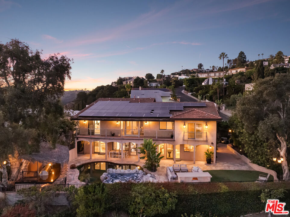 Welcome to 8000 Oceanus, an exquisite residence in the prestigious Mount Olympus enclave with breathtaking cityscape views. Positioned on a coveted corner lot, this nearly 4,000-square-foot home is filled with stunning custom details.Step into a dramatic formal entry featuring soaring cathedral ceilings, elegant chandeliers, and an impressive Onyx stone fireplace stretching from floor to ceiling. Entertain guests in the formal dining room under a dazzling crystal chandelier or ascend the custom wrought-iron staircase to the upper level.The gourmet kitchen is a chef's dream, equipped with top-of-the-line appliances including a Sub-Zero refrigerator, Thermador double oven, 6-burner cooktop with griddle, two warming drawers, granite countertops, and an oversized island with abundant storage and a wine fridge.The luxurious primary suite offers a private sanctuary with a spa-inspired en suite bath, jetted Jacuzzi tub, dual sinks, and two spacious walk-in closets. Step onto your own balcony to enjoy serene views of Downtown L.A. A second staircase off the den leads to a separate private suite, ideal for guests.With a three-car garage plus additional driveway parking, there's room for six vehicles. Outdoors, the meticulously landscaped backyard is perfect for both entertaining and relaxation, offering endless possibilities for gatherings or quiet evenings under the stars. Experience unforgettable sunrises and sunsets while enjoying the best of Mount Olympus living at 8000 Oceanus.