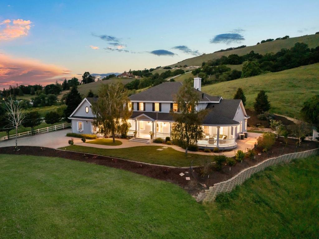 Experience timeless luxury and unmatched privacy at 9560 Via Del Oro, a stunning estate on 10 serene acres in the prestigious, gated Golden Heights Estates. Enjoy breathtaking sunsets and amazing valley and city views. This expansive property features a 5,390 sq ft main residence and a 960 sq ft guest house, offering 5 bedrooms and 5.5 bathrooms. Designed for both elegance and comfort, this gorgeous home boasts soaring ceilings, rich hardwood flooring, a chefs kitchen with granite slab countertops, custom cabinetry, high-end appliances, and travertine floors. The grand living room, formal dining area, and wood-paneled library with fireplace create the perfect setting for gatherings, while two primary suites, including one on the main level, provide private retreats. Outside, the 10-acre lot offers limitless possibilities, from a resort-style pool and vineyard to equestrian amenities or lush gardens. Host unforgettable gatherings with al-fresco dining surrounded by mature landscaping and amazing views. Additional features include an oversized four-car garage, an extended driveway and ample storage. Located minutes from Gilroy Premium Outlets, top wineries, Coyote Lake, and parks, with easy access to US-101 and the Gilroy Caltrain Station. A rare opportunity not to be missed!