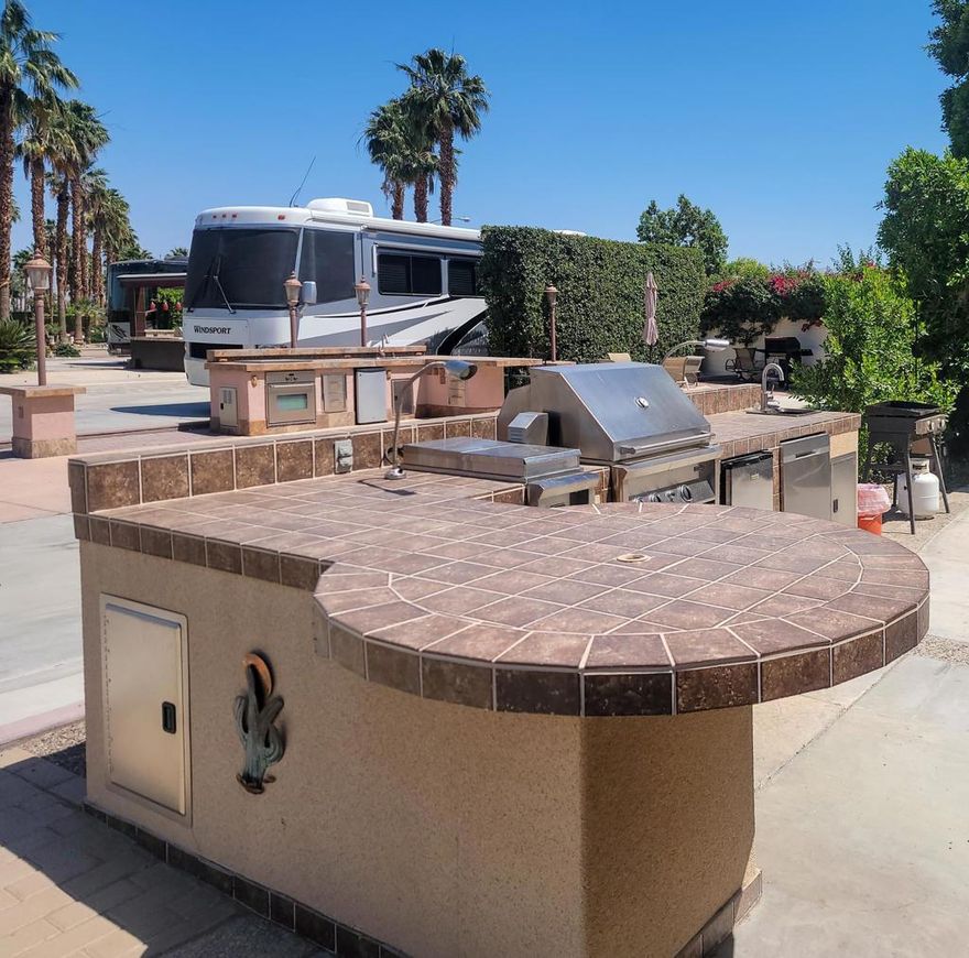 Outdoor Resort Indio is a class A only RV resort and this is an RV lot.Enjoy privacy, comfort, and resort convenience with this beautifully landscaped lot located just a short walk from the satellite pool, hot tub, sauna, and laundry. The inviting medium-sized outdoor kitchen features a round bar with umbrella and four chairs, built-in gas burner and large BBQ, oven, dishwasher, refrigerator, sink, and storage, all enhanced by ample lighting and hot water for effortless entertaining.Multiple seating areas include a dining table with umbrella, an outdoor fire table flanked by two sofas, and additional chairs and side tables--perfect for gathering with friends. This is a private and well-designed lot offering a true resort lifestyle.