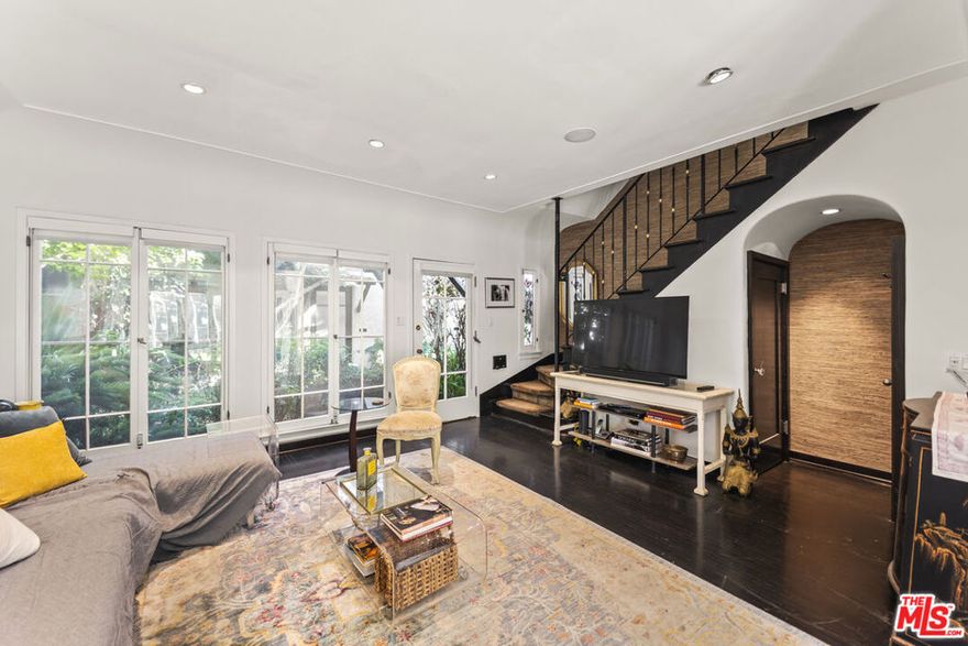 Tucked inside the storybook Norton Garden Villas, this enchanting 1925 townhome offers a rare blend of historic character, lush garden surroundings, and modern upgrades all in one of West Hollywood's most coveted walkable pockets. Through a vine-covered gated entrance, a serene brick pathway leads you to this private two-story residence. The home opens to a sun-filled living room framed by multiple French-pane doors and windows overlooking the beautifully landscaped courtyard. High coved ceilings, ebony hardwood floors and recessed lighting create an elegant yet warm ambiance.A separate formal dining area flows into the renovated European-inspired kitchen, appointed with rich wood cabinetry, Silestone countertops, stainless-steel appliances, a designer metallic tile backsplash, and direct access to the garden pathway. Upstairs, two generously sized bedrooms capture treetop views and abundant natural light. The classic black-and-white bathroom has been thoughtfully updated while preserving its period charm, complete with mosaic tile floors, a pedestal sink, and a beautiful leaded-glass window. Above the upper level is an unusually spacious attic/ceiling volume offering significant storage and potential several neighboring units have remodeled or finished this area (buyer to verify feasibility). Additional highlights include community laundry plus an older in-unit hookup that may allow installation of a stacked washer/dryer (buyer to verify). The quiet central courtyard, gated pathways, and mature landscaping create a peaceful oasis rarely found in West Hollywood.Located just one block from Whole Foods, Post Office, Starbucks, and the Fairfax/Santa Monica corridor, and moments from the Sunset Strip's top restaurants, boutiques, and nightlife, this home offers an unmatched lifestyle of charm, privacy, and walkability. A rare offering homes in this iconic garden complex are seldom available.