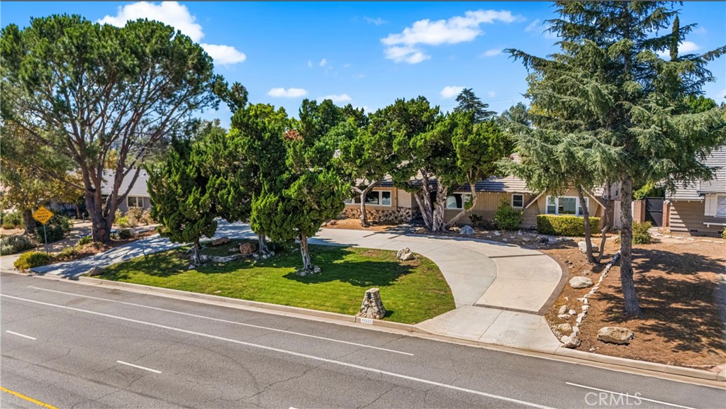 Nestled on a private, beautifully landscaped 1/3-acre lot, this 4 bed 3 bath custom-built rustic home offers the perfect blend of charm, functionality, and comfort. A circular driveway provides ample parking, w/RV access for convenience and privacy. Step through a one-of-a-kind front door into a formal entry, leading to a sun-filled living room featuring a stone fireplace, wood-beamed ceiling, and a wall of windows. Also included is a mounted 86” LG UHD TV with AI ThinQ. The dining room opens to a remodeled gourmet kitchen, featuring a used brick fireplace, built-ins, and elegant Bamboo Hardwood floors extending through the entry, dining room, kitchen, utility room, and hallway. The kitchen is a chef’s dream, boasting double ovens, a 5-burner stove, Kenmore built in refrigerator, self-closing drawers and cabinets, Quartz countertops, an oversized island w/a large utility sink and breakfast bar. A separate laundry/utility offers generous storage and access to a convenient 3/4 bath. All bedrooms are spacious and well-appointed. The primary bedroom includes two closets, one walk in, a custom ceiling fan, and a remodeled bathroom w/dual sinks and tiled shower. Three additional bedrooms and a remodeled hallway bathroom includes double sinks, a tub/shower combination, Bluetooth speaker system. Upgrades include double-pane windows, updated 5-ton high-efficiency HVAC system, Nest thermostat w/updated ducting, Ring camera System, custom oversized hallway linen closet. Step outside to an entertainer’s paradise. The expansive backyard is designed for gatherings of all sizes, featuring a spacious patio with a wood-burning fire pit, a sparkling newly plastered pool with Baja shelf, automatic pool vacuum, autofill, plumbing for heat, and updated equipment, plus an above-ground hot tub. Lush landscaping ensures both beauty and privacy. Additional outdoor amenities include a permitted detached pool house/workshop, a raised garden area shaded by mature trees, beautiful roses, and 2 fruit-bearing orange trees. For convenience and efficiency, the property is equipped with two electrical panels and two water heaters. Located within walking distance to the highly sought-after Granada Hills Charter High School, as well as shopping and dining options, this incredible home combines privacy, luxury, and accessibility in one exceptional package.
