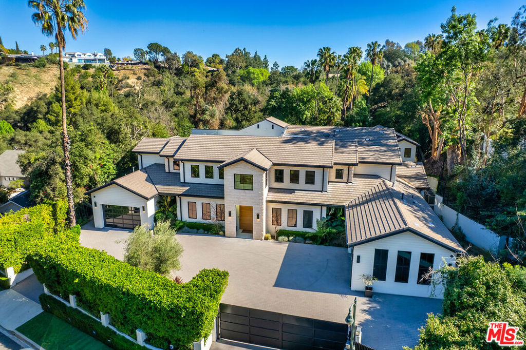 Next-level luxury within the exclusive Royal Oaks enclave of Encino. Situated at the quiet end of a cul-de-sac just off famed Woodvale Road, this private estate caters to the most discerning homeowner with an endless litany of luxurious amenities. Beyond the oversized gates, towering hedges and array of security cameras, the property features dual two-car garages and a custom pivot entry door that reveals an elegant black and white color palette warmed by wide-plank white oak floors, a striking rose gold chandelier, a glass-enclosed wine cellar, and a captivating view of the exceptional outdoor entertaining space. Artfully designed and meticulously crafted, this light-filled California contemporary home features an open, modern floor plan and a true chef's kitchen with two islands. The formal entry flows into the living room and a chic bar area, accented by bespoke black brickwork. Enjoy an immersive experience in the state-of-the-art home theater. There are three main level bedrooms to accommodate family members or staff. This eight-bedroom residence also has an elevator connecting the first and second levels, and includes a stunning second-level primary suite with a fireplace and a fashionista-worthy closet. Disappearing sliding doors open to a second floor private balcony with views of the serene grounds and no other homes or yards. An additional 1100 sf rooftop loft with outdoor kitchen, built-in bench seating, and space for a huge outdoor screening space, which provides a secluded setting for al fresco dining and views of starlit nights. It's the perfect place for the kids to have their own entertaining area within the safe confines of the property. The beautifully landscaped backyard features a sparkling pool, covered bar, outdoor lounge, lots and lots of space for resort-style chaise lounging, a ping pong area, and a great half-court basketball court. The detached two-story guest house offers 1,400 square feet of additional living space, with a gourmet kitchen with barstool seating, living room, laundry, two bedrooms and three bathrooms, a private retreat in itself. It truly is a second home on the property. Lush landscaping and meticulous detail define this exceptional property, offering incomparable design, privacy, and lifestyle in a premier location. It's exclusive, it's elevated, it's bespoke design meets secluded comfort.