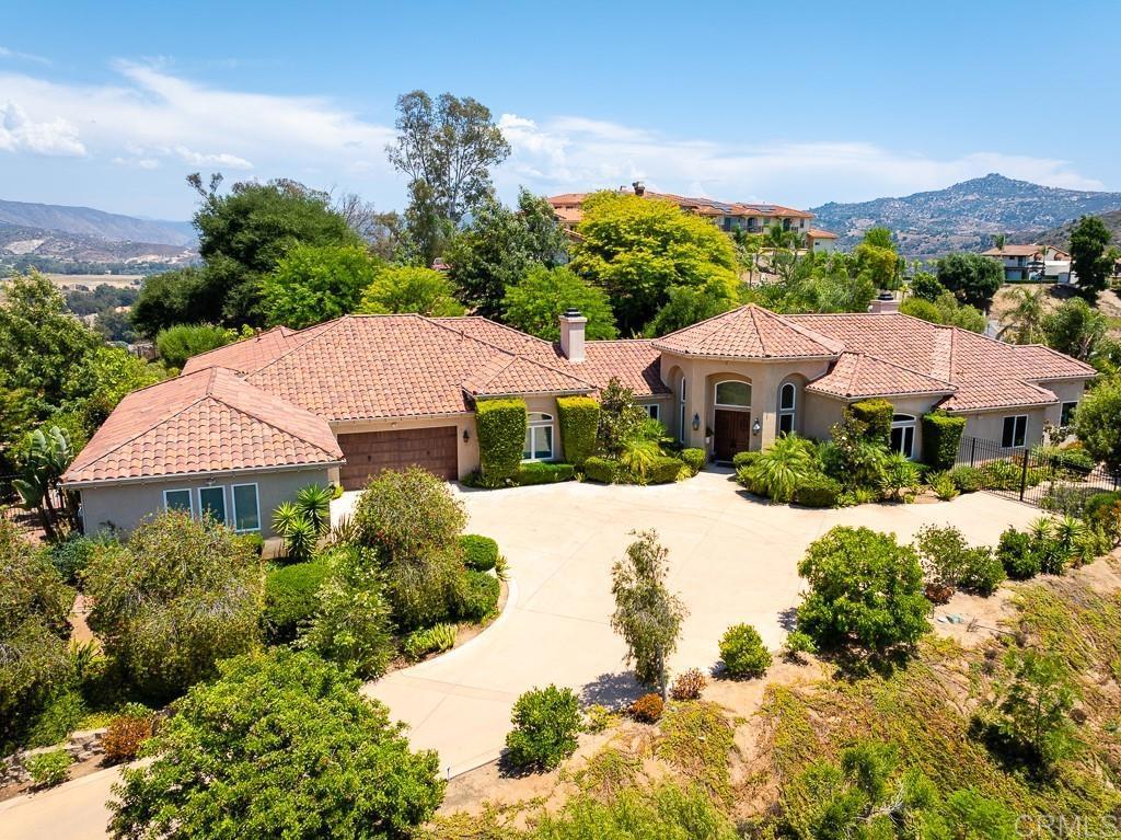 Welcome to this 5,713 square foot private gated estate on over 30 acres overlooking the San Pasqual Valley. This custom-built single-story home boast five bedrooms, four full bathrooms, two half baths, two extra rooms which can be used as offices or game rooms, formal living room, formal dining room, a grand entry with 14-foot ceilings, family room, kitchen, breakfast nook, and a chilled wine closet. The chef’s kitchen is equipped with an eight-burner dual fuel stove, 48-inch wide custom exhaust hood, two dishwashers, side-by-side 72-inch wide built-in refrigerator and freezer, an island with sink and garbage disposal and seating for four, butler pantry, built-in microwave, warming drawer, and separate walk-in pantry. Built-in stereo inside and outside, central vacuum, three fireplaces, recessed lights, ceiling fans in all bedrooms and the family room and dual pane windows throughout. Clay title roof, high ceilings, crown moldings and a combination of marble and tumbled travertine floors throughout the home. The family room opens to a 600 square foot covered porch with built-in barbeque and spectacular views. The attached oversized four-car garage consists of approximately 1,295 square feet of space and features built-in cabinets and countertop with a sink and a second clothes washer. There is ample space in the garage for extra storage. Large room sizes throughout. The saltwater pool and spa feature both a propane fired 400,000 btu heater and solar heating panels by Mark Naylor. The yard around the home is fenced with custom metal fencing. The driveway has two electric gates. The gate to the driveway to the home is controlled by a keypad, clicker or a remote application from your phone. Owned 40-panel ground-mounted electric solar under Net Metering One means no electric costs. 24 KV Generac propane powered generator with automatic transfer switch provides power when SGD&E has an outage. Three separate newer Trane air-conditioning units with individual thermostats. Hauge water softener. Exterior flood lights on motion sensors turn on exterior lights as you walk around the outside of the home at night. Gutter lights wrap the complete exterior of the home. Room to add additional buildings including an ADU. No HOA dues, no Mello Roos, low property tax rate. Walking distance to the Hungry Hawk Vineyard & Winery. Convenient to the San Diego Zoo Safari Park, Route 78 and to the 15 via the Via Rancho Parkway Exit. Primary bedroom: 22 x 18. Primary bedroom library: 13 x 11. Primary bedroom closet: 12 x 11. Bedroom two: 15 x 13. Bedroom three: 15 x 13. Bedroom four: 15 x 13. Bedroom five: 24 x 16. Extra room one: 19 x 15. Extra room two: 14 x 14. Family room: 22 x 19. Living room: 19 x 18. Dining room: 16.5 x 15.5. Kitchen: 24 x 19. Breakfast nook: 13 x 11.