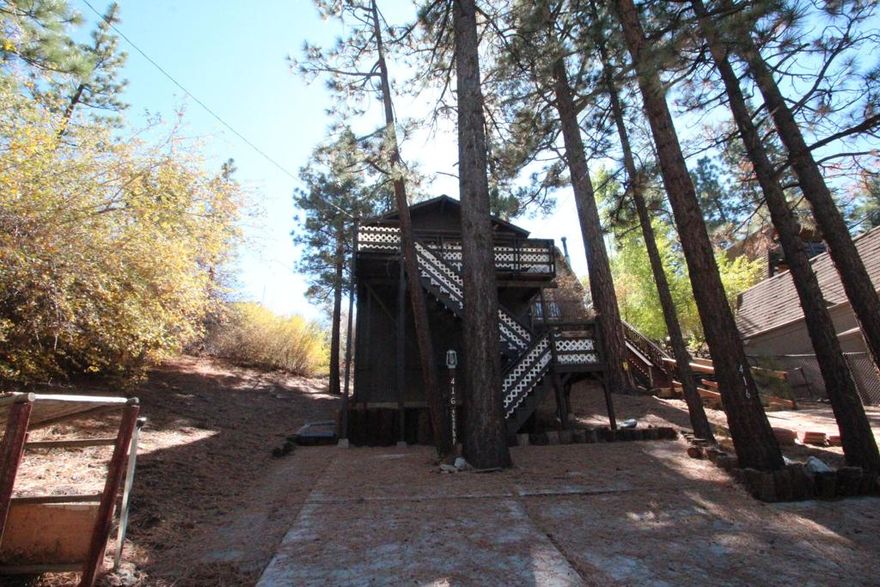 This Elevated Cabin Offers A Prime Location Near The Popular Big Bear Oktoberfest (Big Bear Convention Center Which Hosts Many Community Events Throughout The Year). It Features Two Bedrooms, One Of Which Provides Access To A Good Sized Back Deck With Peaceful Views, Along With A Full Bathroom. The Living Room Has A Floor To Ceiling Corner Rock Fireplace, Plenty Of Seating Area And Breakfast Bar Eating Area. There Is Plenty In This Big Bear Cabin. The Property Boasts A Deep Lot That Backs Onto A Vacant 20-Acre Parcel. Additionally, The Cabin Has A Spacious Under-Area Currently Used For Storage With Washer/Dryer Hookups, Which Could Be Renovated To Create Additional Living Space. The Cabin Is Conveniently Located Close To Bear Mountain Ski Slopes, Golf Course, Big Bear Lake, And The Village.