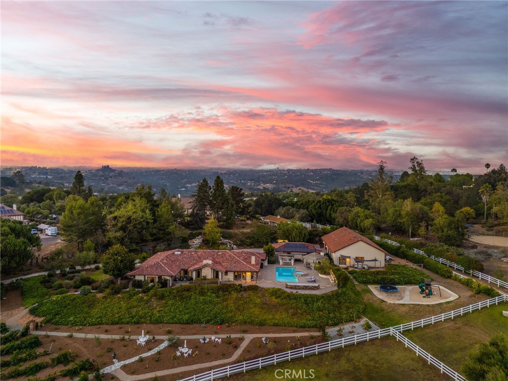 Welcome to 4 Golden Meadow Lane, Fallbrook — a private estate in the prestigious guard-gated community of Rolling Hills Estates, where country charm meets luxury living in an equestrian-friendly setting.
This single-story residence, with OWNED SOLAR, sits on a 2.57 acre beautifully landscaped, expansive lot designed for both relaxation and recreation. The main home offers bright, inviting living spaces with thoughtful details throughout. A separate full shop with its own living quarters includes one bedroom and two flex rooms; perfect for guests, extended family, office space, or hobbies.
The backyard is an entertainer’s dream — complete with a sparkling pool and spa, a fully equipped outdoor kitchen, and a dedicated pool house for guests or recreational use. Beyond the pool area, the property unfolds into a private vineyard and an assortment of mature fruit trees, creating a picturesque setting and the opportunity to enjoy your own fresh harvests.
For equestrian enthusiasts, this property is a rare find — horses are permitted on-site, allowing you to keep your horses at home and enjoy direct access to the neighborhood’s private horse trails. The community also boasts a full equestrian center for boarding, training, and events.
Living in Rolling Hills Estates means enjoying a wealth of amenities, including:
Guard-gated entry with 24-hour security, Miles of scenic horse and walking trails, Golf cart-friendly streets, Pickleball and tennis courts, Clubhouse for community gatherings, A tranquil pond and lush green spaces, RV parking available for residents.
Whether your perfect day includes a morning ride, an afternoon swim, tending your vineyard, or entertaining friends under the stars, this home offers a rare combination of space, lifestyle, and privacy — all in one of Fallbrook’s most sought-after communities.