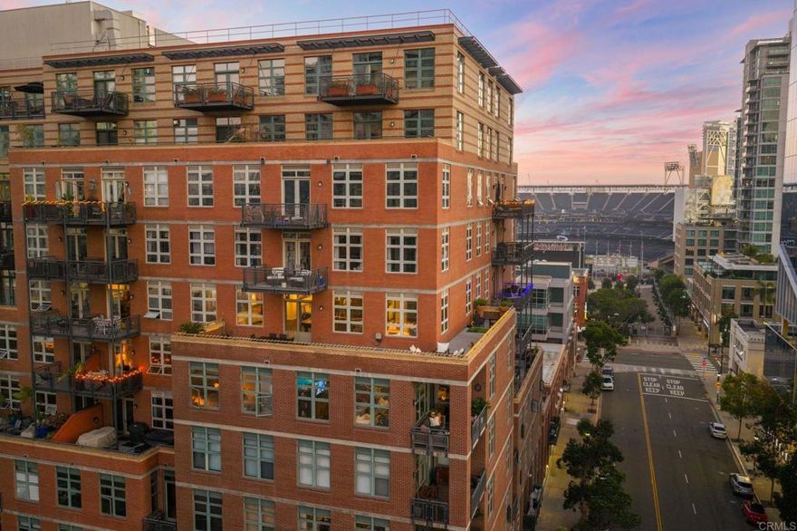 Premier Parkloft residence with an expansive wrap-around 900 sq. ft. balcony — a true extension of your living space. This rarely available Northwest corner unit offers nearly 2,500 sq. ft. of combined indoor and outdoor living, perfect for entertaining before an event at Petco Park or hosting under the striking city lights.  Step inside to an open loft-style layout featuring 10’6” ceilings, solid oak flooring, and luxurious custom upgrades throughout. The Studio Becker kitchen showcases a gas stove, new custom cabinetry providing a massive amount of storage, and premium finishes throughout. The home also includes a washer and dryer, two top-of-the-line 55” Sony OLED TVs, and a built-in sound system for an immersive audio experience. Custom lighting sets the perfect ambiance across the space.  The space is thoughtfully designed, featuring exposed brick walls that add warmth and character and windows that bring the outside in. From the wrap around balcony enjoy listening to live music from nearby concerts or watch the planes fly in from the east. Double-pane windows ensure a peaceful retreat while indoors, away from the hustle and bustle.   Enjoy Parkloft’s first-class amenities including TWO parking spaces, a 24/7 lobby attendant, fitness center, and beautifully landscaped courtyard with BBQs — all in the heart of East Village, just steps from Petco Park this is the heartbeat of San Diego.