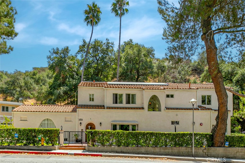 Set in the coveted Chevy Chase Canyon, this Spanish-style residence blends timeless character with sophisticated updates. The striking front door opens to an original tiled foyer, leading into a dramatic living room with vaulted ceilings, fireplace, and French doors to a private patio. Original wood floors and paneled walls in the formal dining room preserve the home’s 1930s charm, while the kitchen offers classic tile counters, a central wood island, and breakfast nook with new French doors opening to a patio retreat.
The main level features a bedroom, full bath, and spacious family room with fireplace, wet bar, and an office. Upstairs, the primary suite showcases a walk-in closet and bathroom, accompanied by a secondary suite bedroom, laundry room, and oversized garage. An attached casita with private entry, bath, and patio provides additional living or studio space.
Modern enhancements include new windows and doors, Recessed lighting, Tesla solar panels, energy-efficient HVAC, newer water heater, and a full interior sprinkler system—seamlessly blending original craftsmanship with today’s conveniences. Surrounded by lush greenery, gated front yard, and grassy side yard, this home offers elegant canyon living at its finest. Must see