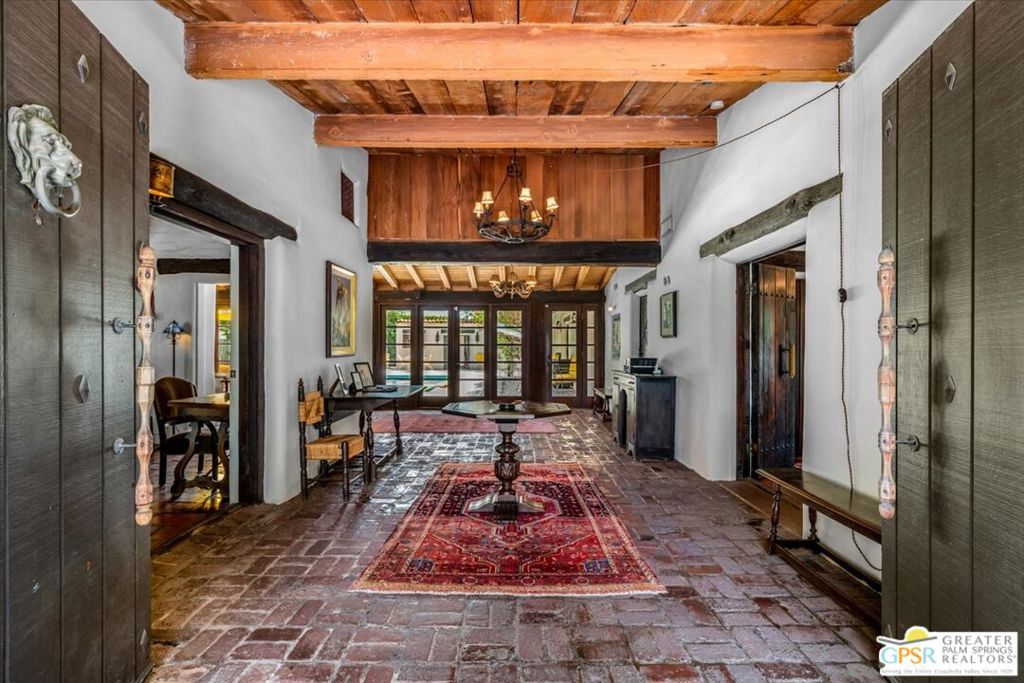 This classic, 1934 architectural Old Spanish Hacienda mini-estate enjoys a long fabled Hollywood history and is appropriately located in the central Palm Springs neighborhood known as Movie Colony East. This home retains most of its original charm and character and offers what Palm Springs is most known for...gracious spaces for entertaining indoors and out, plus total privacy. Vaulted, beamed ceilings set the romantic style from the moment you enter as your gaze carries you through a wall of multi-light French doors out to the resort-sized pool. The large living room suggests a set from a film with its decoration thoughtfully designed, all focused on the tiled fireplace surround. The L-shaped home embraces the pool and yard and allows access from all parts of the home: Entry hall, dining room, kitchen, and pool changing room and its bath. On the other leg of the "L" are 4 bedroom suites, two or three with outdoor access ala pure Hacienda style , and their 3 baths. The Cantina is a charming addition to the poolside, and doubles as a pool storage space and laundry. Indoors, off the kitchen is a large screening room with projector, which makes it popcorn-adjacent! This home is for those who respect and appreciate authenticity and era-specific architecture. Here's to the good life. Come rediscover it.