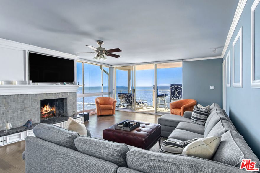 Set directly above the sand on Malibu's famed Carbon Beach, this top-floor corner residence at the exclusive Malibu Outrigger offers front-row panoramic ocean views stretching from Santa Monica to Catalina Island, with sightlines also capturing LAX and Palos Verdes. A rare opportunity in one of Malibu's few complexes with direct beach access and resort-style amenities, this sunlit condo blends timeless coastal charm with modern design. The open-concept living area features expansive walls of glass that frame endless blue horizons, a cozy fireplace, and seamless indoor-outdoor flow to a private oceanfront balcony perfect for morning coffee, outdoor dining, or watching dolphins play at sunset. The kitchen is beautifully designed with custom white cabinetry, granite countertops, and a stunning glass-tile backsplash.The ocean-view primary suite opens to the balcony and features a spa-like bath with dual vanities and a striking  steam shower with Bose music system, clad in stone mosaic tile. A versatile second room doubles as a guest space or home office with built-ins, generous storage, and incredible coastline vistas. At the Malibu Outrigger, residents enjoy a heated oceanfront pool and spa, direct sandy beach access, an on-site management team, and an unparalleled location close in proximity to Soho House, Nobu, Malibu Pier, and the Country Mart. One covered parking space plus surface lot parking for additional cars and secure entry complete this rare beachfront offering.