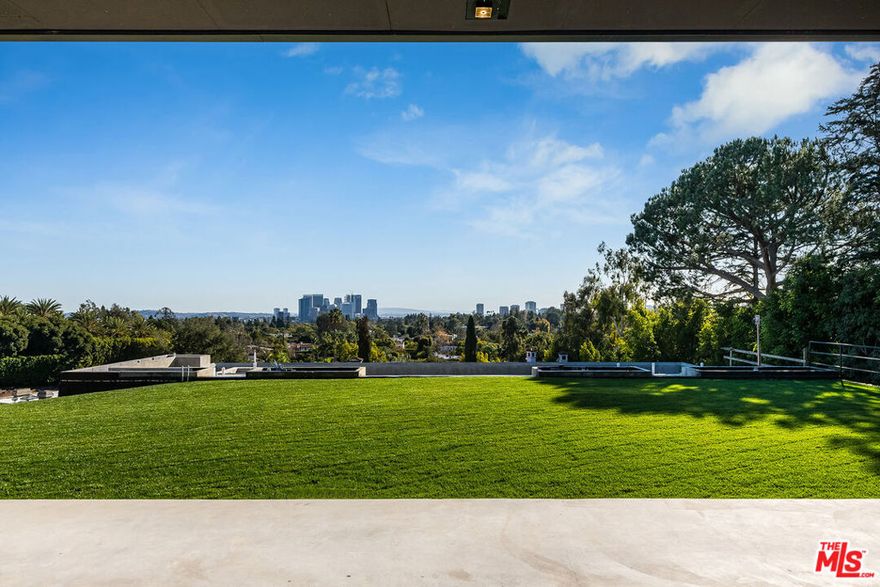 Nestled in the heart of prime Beverly Hills, this exceptional estate offers the rare opportunity for a fortunate buyer to personalize a magnificent home. Spanning apx. 15,000 sq. ft. on a sprawling apx. 1.35-acre lot, this Contemporary estate is designed by renowned architect Richard Landry, known for his timeless and luxurious creations. Enter the estate through private gates and up a long winding, private driveway to a spacious motor court. The home is in the final stages of construction, with plans and permits fully approved and major structural elements already completed. The framing, facade, floor plan, walls, windows, electrical, and plumbing are all in place - leaving the exciting opportunity for the buyer to select their own finishes. The striking facade features walls of glass and exquisite split-faced travertine quarried and cut in Italy, including silver travertine accents, setting the tone for a sophisticated and modern design. Upon entry, a grand two-story foyer welcomes you with soaring ceilings and walls of glass throughout the home, providing seamless access to the outdoor spaces and stunning head-on views that span from the city to the ocean and beyond. The main level offers expansive living areas, including a grand great room with a fireplace, a media room, and a library with fireplace. There are also four powder rooms, a large office with an en-suite bathroom, and both a chef's prep kitchen and a family kitchen with adjoining breakfast area and family room with fireplace. The main level's exterior space is equally impressive, featuring a large covered loggia with a fireplace, an expansive game and bar area, and a spectacular infinity pool and spa, perfect for entertaining or relaxing while enjoying the panoramic views. Ascend or descend the grand staircase or take the elevator to all three floors. The upper level of the home features four bedrooms each with en-suite bathrooms, including the primary suite complete with sitting room with fireplace, dual bathrooms, enormous walk-in closets, and a private terrace. A large gym with an en-suite bath offers flexibility as an additional bedroom or office. The lower level is designed for ultimate entertainment and relaxation, with a vast playroom, a wine room, and a spa complete with a lounge area, treatment room, steam room, and sauna. The lower level also houses a staff lounge with an en-suite bathroom, a laundry room, mechanical rooms, ample storage space, and a massive garage with space for at least eight cars. For added privacy and convenience, there is a detached guest house featuring a three-car garage on the lower level and a spacious upper-level bedroom and bathroom with its own private terrace. Adjacent to the guest house, a sport court offers an additional amenity for active living. This is a once-in-a-lifetime opportunity to finish crafting your dream home in one of Los Angeles' most desirable locations. With its prime Beverly Hills address, stunning architectural design, and unparalleled views, this estate represents the epitome of luxury living.