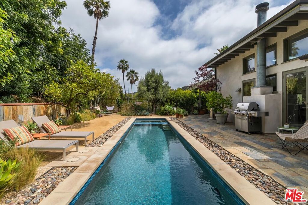Exceptional, architect-owned, custom-designed Mid-Century gem on a 10,000+ SF Lot in highly coveted Laurel Canyon, known for its creative community and top-rated Wonderland School. The beautifully landscaped front garden, with native plants and raised boxes with fresh herbs & vegetables offers a striking yet serene welcome. This meticulously cared for home features designer finishes, custom doors/windows high ceilings, skylights, and a seamless floor plan flooded with natural light. At the heart of the home is a gourmet kitchen with bulthaup cabinetry, center island, Sub-Zero fridge, Bosch double oven, Miele dishwasher, Gaggenau gas cooktop, and walk-in pantry, perfectly positioned to face a spacious family room, creating a central hub where family and friends come together. Whether it's Sunday breakfast, holiday gatherings, or game night, it's the kind of space where memories are made. The living room offers a cozy fireplace and garden views. Featuring three bedrooms with custom built-ins & roomy closets, two designer baths and a thoughtfully designed hallway workspace with built-in desk and storage. Gorgeous private backyard with a newer lap pool/spa and plenty of space to BBQ, dine al fresco, or simply unwind after a busy week. Other highlights include a newer roof, new 5-Ton heat-pump rooftop packaged HVAC, 2 car garage with 2 EV chargers, fully paid off solar panels, 3 fireplaces, and security package with CCTV monitoring system. This prime Hollywood Hills location is located steps from Mulholland Drive with easy access to Sunset Boulevard, Beverly Hills, Studio City, hiking trails, Mulholland Tennis club and the Wonderland School.