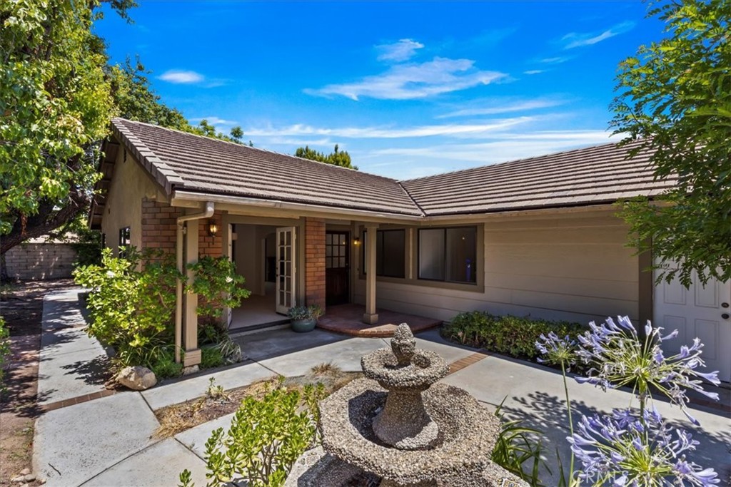 Charming single-story home featuring 3 bedrooms and 2 bathrooms. This popular floor plan welcomes you with a private gated front courtyard, complete with a soothing water feature and a covered porch perfect for relaxing outdoors.
Inside, the kitchen offers bar seating and opens to a dining room with French doors looking out to the relaxing courtyard, while the spacious family room boasts vaulted ceilings, a warm fireplace, and direct access to the private backyard—ideal for entertaining or quiet evenings at home.
The generous primary suite includes a large closet and an ensuite bathroom. Two additional spacious bedrooms share a convenient guest bath. An attached 2-car garage provides ample storage and parking.
Move-in ready with fresh paint and new carpet throughout, this home offers a blank canvas to add your personal touch and style.
Located in a wonderful community featuring scenic walking paseos that connect you to three community pools, parks, and recreation areas. Enjoy proximity to the mall, shopping, vibrant Valencia nightlife, award-winning schools, and Henry Mayo Hospital.