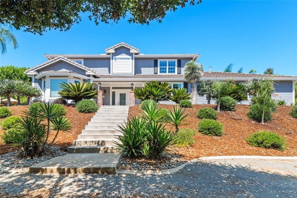 Nestled on a fully fenced 1-acre lot in the heart of Fallbrook, this 4-bedroom, 4-bath, 3,331 sq. ft. home offers scenic views and timeless country charm. Built in 2002, it features dual-pane windows, crown molding in every room, stained glass panels, porcelain tile floors downstairs, a formal living room, formal dining room, and a bright family room with a wood-burning fireplace and 8-ft. sliding door leading outside. The gourmet kitchen boasts granite counters, Bosch appliances, a walk-in pantry, a large center island with pull-out cabinets, a reverse osmosis system, and a whole-house water softener. A spacious downstairs bedroom with a remodeled bath featuring a walk-in shower just steps away provides ideal guest or multi-gen space. Upstairs, each bedroom has its own full bath, with the primary suite showcasing a walk-in closet, remodeled bath with walk-in shower, Jacuzzi tub, and new quartz counters. Outdoor living features beautiful landscaping, two covered patios, a built-in BBQ, and a tranquil backyard ideal for entertaining or relaxing. In addition to the main driveway, the property offers a separate parking area with room for multiple RVs, equipment, toys, or a great space to add a horse stall. Additional highlights include a 3.5-car garage, an 8' x 20' storage container with siding to match the house, dual HVAC systems, whole house back up generator, and an electric gated entry—all just 5 minutes from Mission Rd. and the 76, in a prime Fallbrook location known for its wineries, orchards, and peaceful lifestyle.