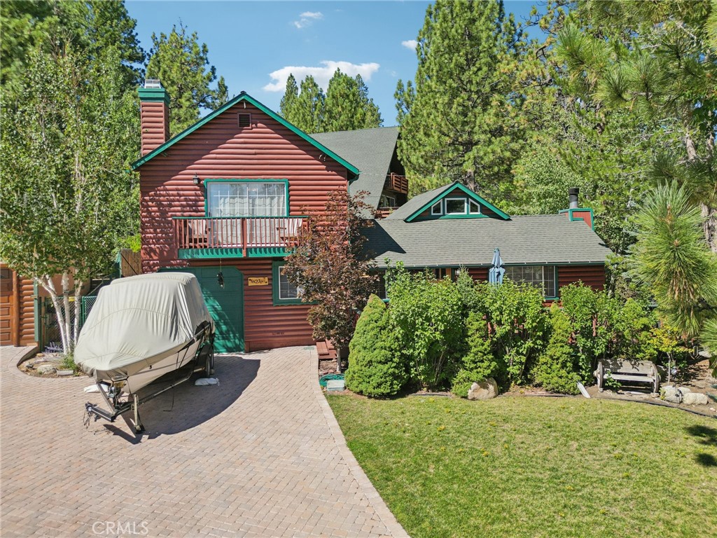 Charming Log Cabin with Lake Access & Village Location! This beautifully rustic log cabin offers the ultimate mountain lifestyle with lake access just down the street and a quick 5-minute stroll to the Village for dining, shopping, and live music. Perfectly blending charm and comfort, the home features a spacious front deck, fenced backyard with firepit, and a paver driveway with room for cars and even a boat—plus an attached 1-car garage. Go inside to enjoy the warm ambiance of a gorgeous stone fireplace with wood mantle, great natural light, and an open kitchen and dining area. The main level includes two bedrooms and a full bathroom, with one bedroom featuring a ladder to a unique loft space ideal for a game room or additional sleeping area. Upstairs, the privately situated primary suite is a true retreat with its own stone fireplace sitting area, en suite bathroom, and a slider leading to a balcony with fresh mountain views. Whether you’re seeking a full-time residence, vacation getaway, or investment property, this cabin offers an unbeatable location and classic Big Bear charm.