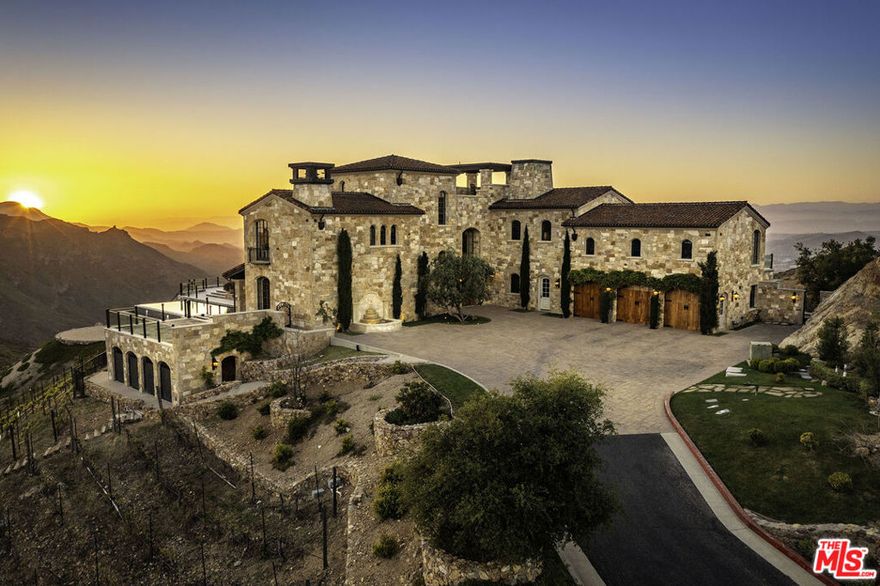 Welcome to Malibu Rocky Oaks, a landmark vineyard estate situated on over 37 acres of verdant rolling hills and terraces in the heart of Malibu wine country. This remarkable estate is situated behind grand custom iron gates, up a wide apx. 350 foot long driveway, and perched on a knoll overlooking breathtaking views of the Malibu canyons, peaks, and the Pacific Ocean. Designed by renowned architect Bob Easton, AIA, this one-of-a-kind stone-clad Tuscan villa consists of over 7,600 sqft of living space offering grand scale living with elegant proportions and infinite possibilities for entertaining and opulent year-round indoor-outdoor living. Offering the perfect blend of old-world elegance and European quality with modern luxury and amenities, the home has been designed to maximize the natural light and showcase the encompassing and expansive views throughout. Enter into the formal foyer, past the formal dining room and into the expansive great room with cathedral ceiling, towering stone fireplace, and surrounding walls of glass leading to the incredible observation decks. The gourmet commercial-grade kitchen features professional appliances, "eat-in" island, and adjacent butler's pantry. The luxurious primary suite features a spa-like bathroom, salon, generous walk-in closets, and private terrace with fireplace. There are three additional guest bedrooms suites plus staff quarters as well a media room, elevator, spectacular roof-top observation deck with 360 degree views, spacious three-car garage and oversized guest parking. The exterior features include wrap-around decks, loggia with fireplace, dining area, beautiful infinity edged pool and spa, and circular observation pad. The property consists of over 37 acres of picturesque grounds including apx. 9 acres occupied by the Malibu Rocky Oaks Vineyard which produces several award-winning varietals. Established in 2003, the legacy of this vineyard has flourished. This vineyard is one of more than fifty vineyards located in the esteemed Malibu Coast American Viticultural Area where the first known Malibu Coast vineyard was planted in the early 1800's. The Malibu Coast American Viticultural Area's nutrient-rich soil and Mediterranean microclimate allow the ideal conditions for growing premium wine grapes. Malibu Rocky Oaks Vineyard is one of the region's most acclaimed vineyards producing award winning wines that have gained recognition for their quality. A must see for any discerning buyer looking for a spectacular Villa estate.