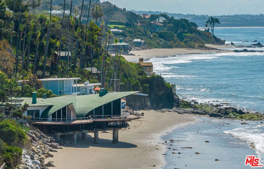 An architectural masterpiece. One of the most iconic properties on the California coast. The Wave House is the design of visionary architect Harry Gesner. Offered for sale for the first time in nearly 36 years. An avid surfer throughout his life, Gesner famously designed the house to emulate cresting waves. The house was completed in 1963 and exudes a mid-century modern aesthetic throughout emphasizing open space and natural light. Tucked into a hidden cove in Western Malibu, the home commands majestic views of the ocean waves, distant islands and surrounding landscape. The residence has two distinct parts. Three enormous oceanfront vaulted public rooms and a stunning beachfront primary suite with hot tub and sauna, plus a five-bedroom upper level that stretches the width of the property to offer ocean views from nearly every room. Architectural elements include enormous beams, wood-plank ceilings rest above hardwood floors and walls of glass with ocean beyond. Perhaps the most distinctive design theme is a series of overlapping circles. Three wraparound decks echo the shape of the incoming surf. The sunken conversation pit swirls around its central fireplace. Even the shape of the hand-cut copper shingles that cover the roof resemble the scales of a fish. A separate garage/guest house structure offers additional bedrooms. Providing the very essence of coastal living, the home features an expansive, landscaped entry patio, plus wide, semicircular decks for dining, entertaining, lounging, and sea and stargazing. Shown only to prequalified buyers.