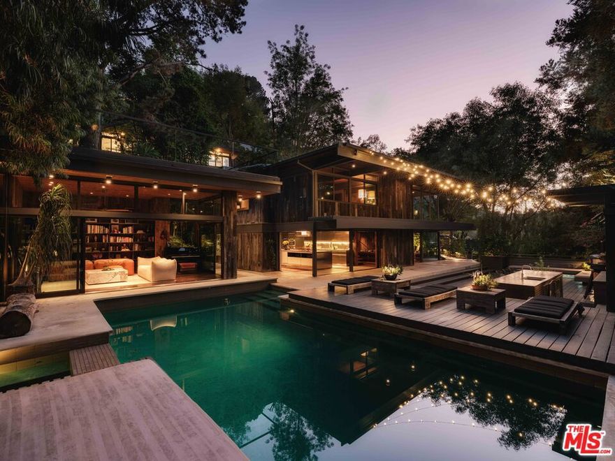 "The Ajioka House" a 1960 post-and-beam by Buff & Hensman, meticulously restored and reimagined by Commune Design. Privately tucked behind gates on nearly an acre of lush, landscaped grounds, this architectural compound unfolds across 4 detached structures: the main residence, guest quarters, and studio dwellings which are linked by lush garden pathways, sculptural fire features, and two custom Stan Bitters water installations.  Each space is thoughtfully composed to celebrate light, material, and connection to nature. Interiors are wrapped in reclaimed oak cladding, grounded by polished concrete floors, exposed beams, and a dramatic brick fireplace that anchors the main living area. At the heart of the home, a 24-foot Boffi kitchen island of stainless steel and walnut serves as a sculptural centerpiece, opening effortlessly to expansive outdoor living areas, an open-air bar, and a collection of serene spaces for gathering and retreat. Surrounded by mature landscaping and canyon vistas, the property offers a profound sense of peace and privacy. Just moments from the iconic Sunset Strip, The Ajioka House endures as a preserved architectural landmark, embodying the clarity, craftsmanship, and enduring vision that define Buff & Hensman's most celebrated works.